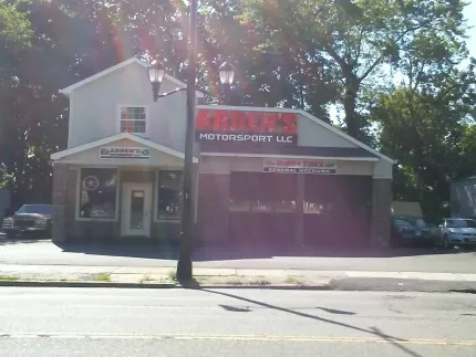Street view of a small corner storefront with a red awning and parked cars in front.