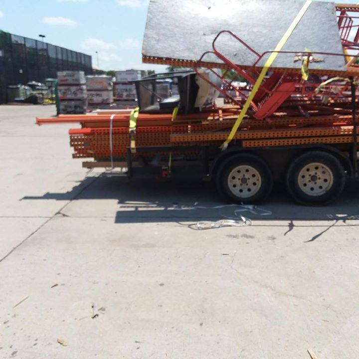 Trailer loaded with orange scaffolding and building materials, parked on concrete