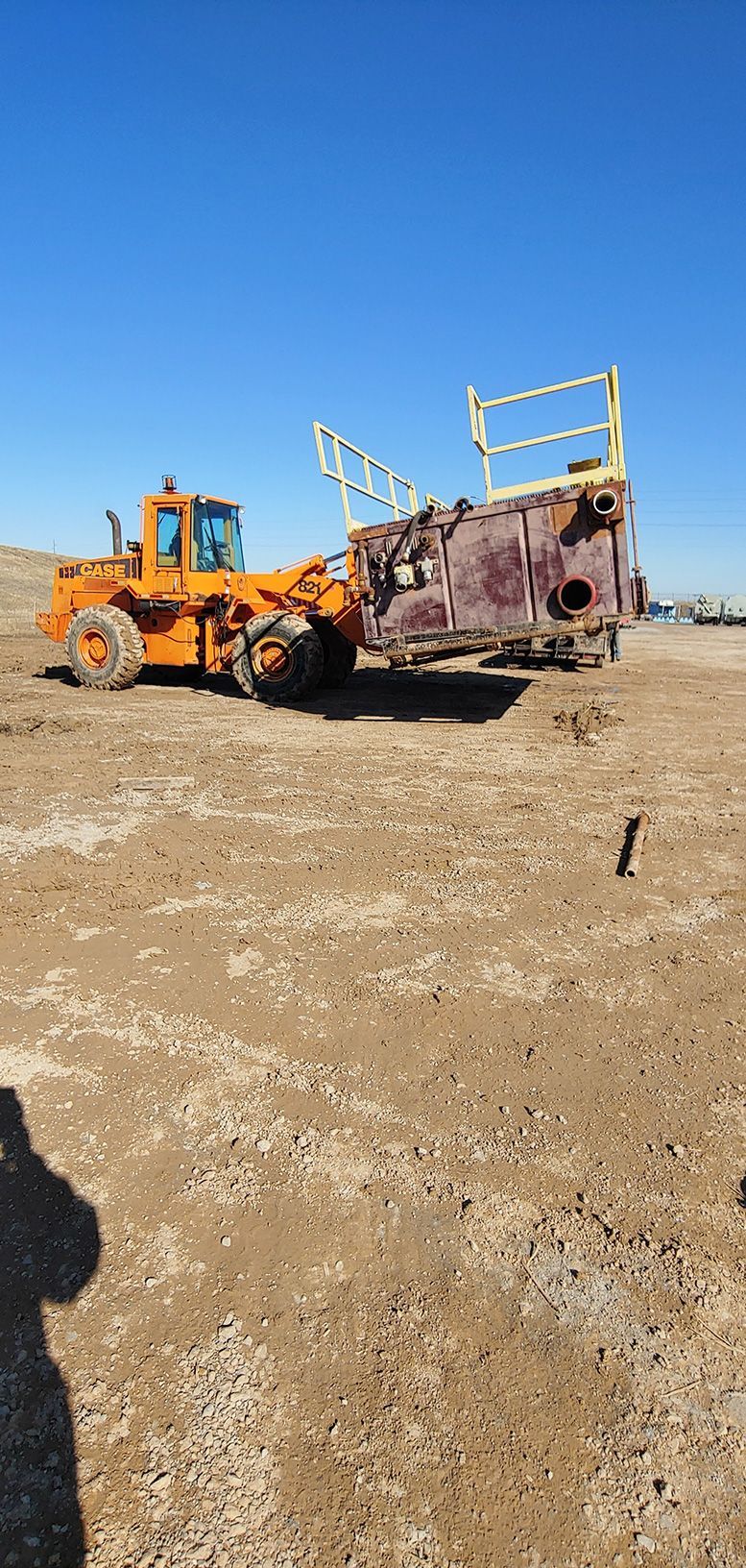 An orange front-end loader carrying a large metal box