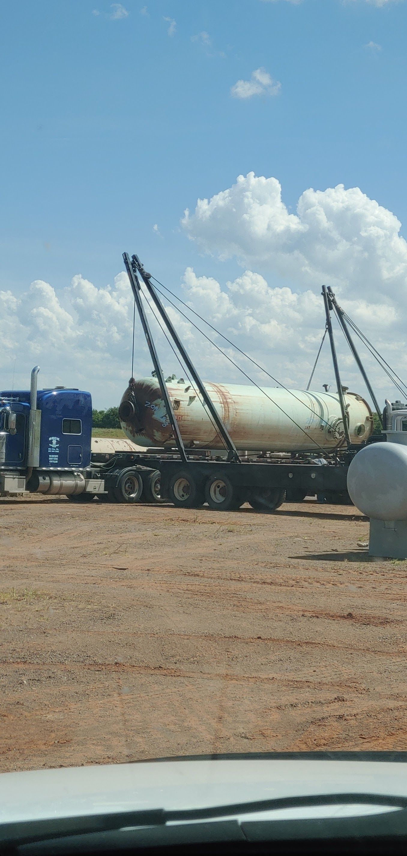 A truck hauling a large cylindrical tank on a flatbed trailer