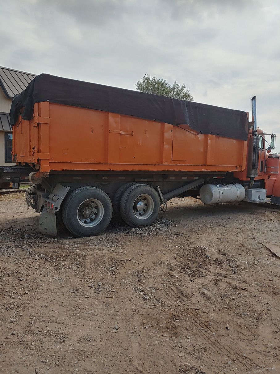 Orange dump truck with a black tarp covering the cargo area