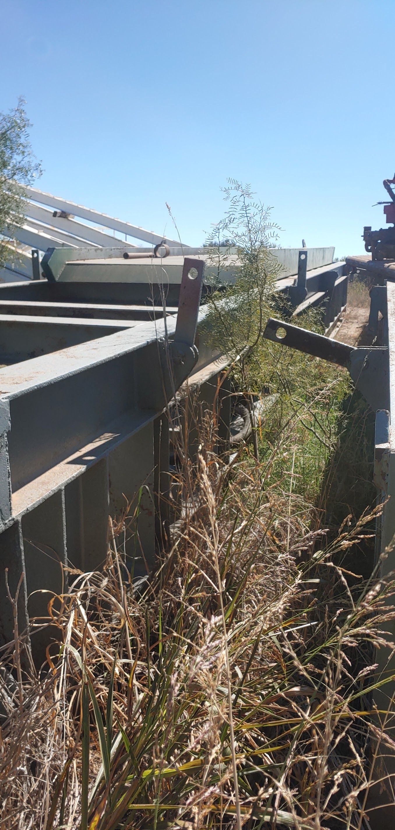 Metal structure partially obscured by tall grass against a blue sky