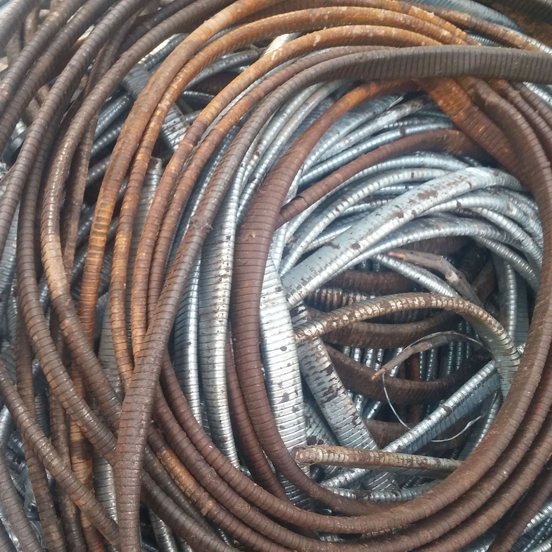Tangled pile of weathered, corrugated metal tubing in shades of brown and silver