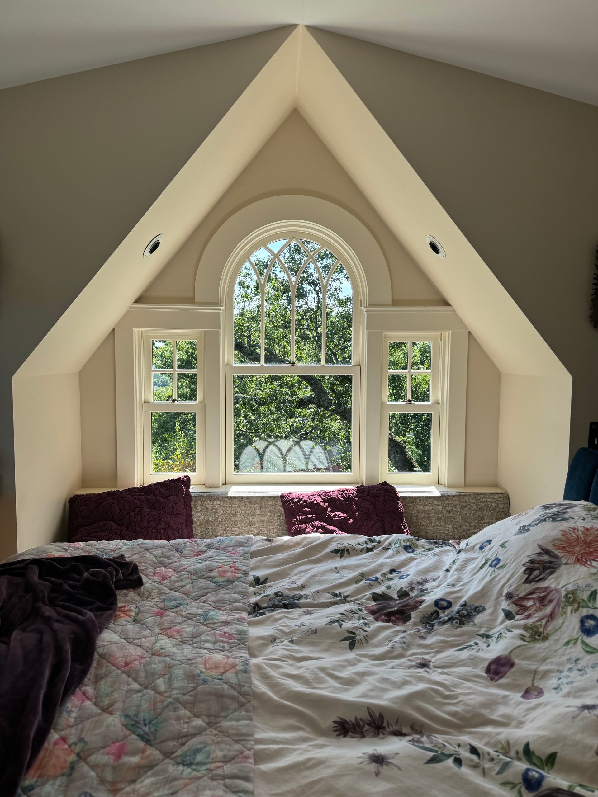 A bedroom with a bed and a window in the corner.