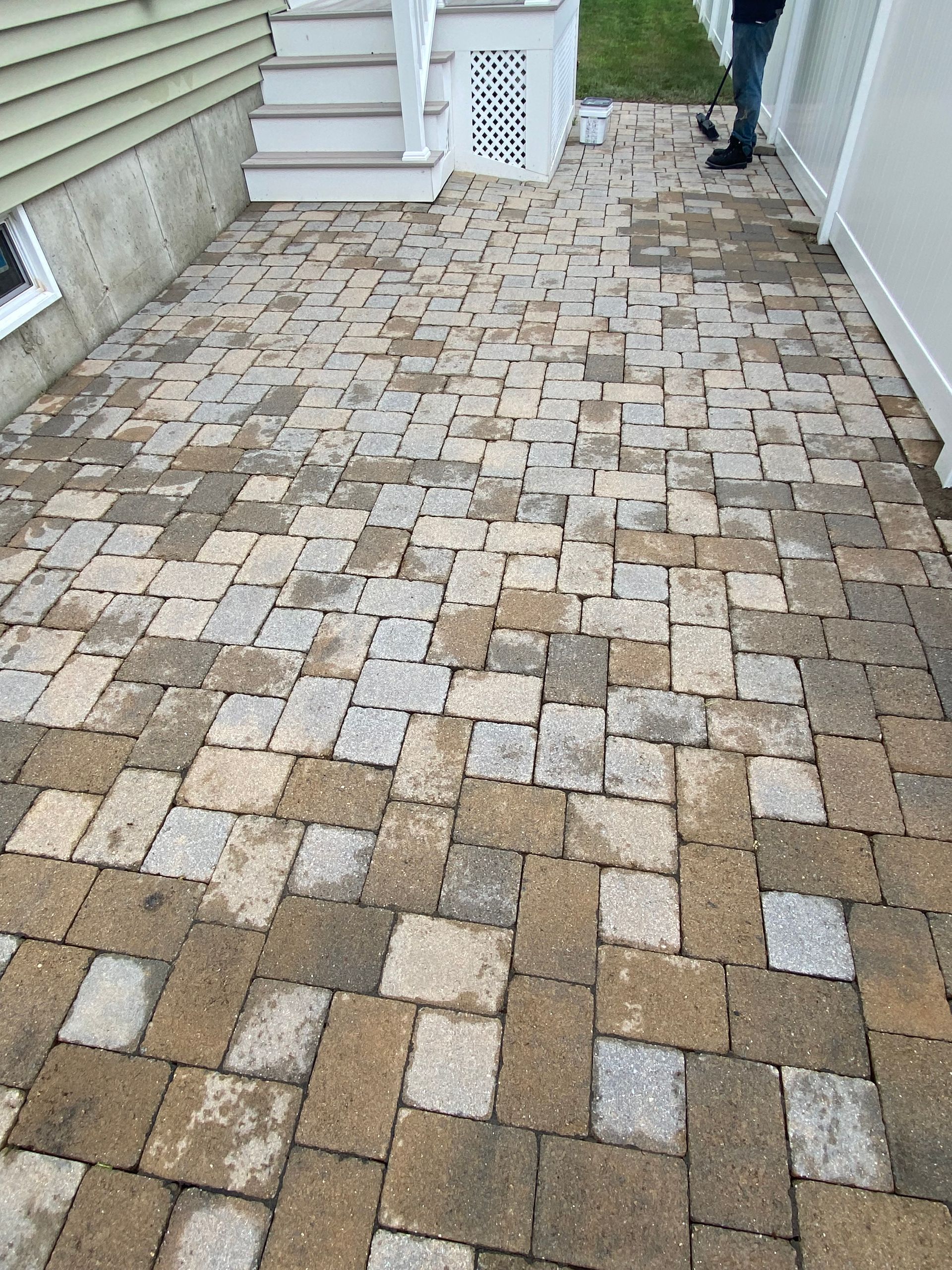 A person is standing on a brick walkway in front of a house.