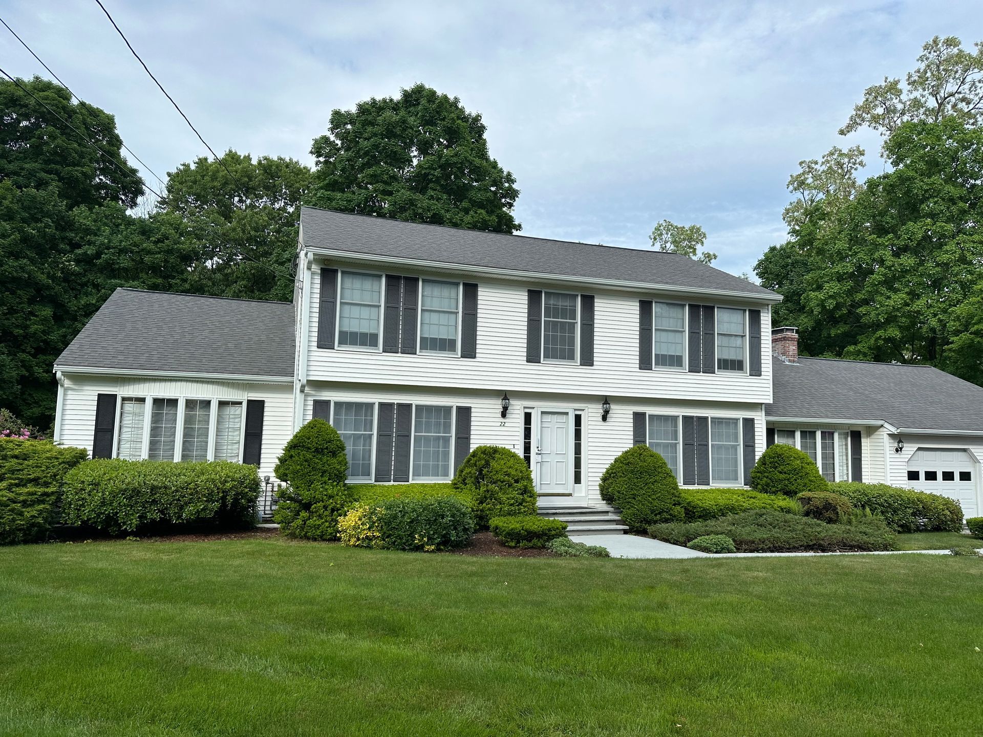 A white house with black shutters and a gray roof.