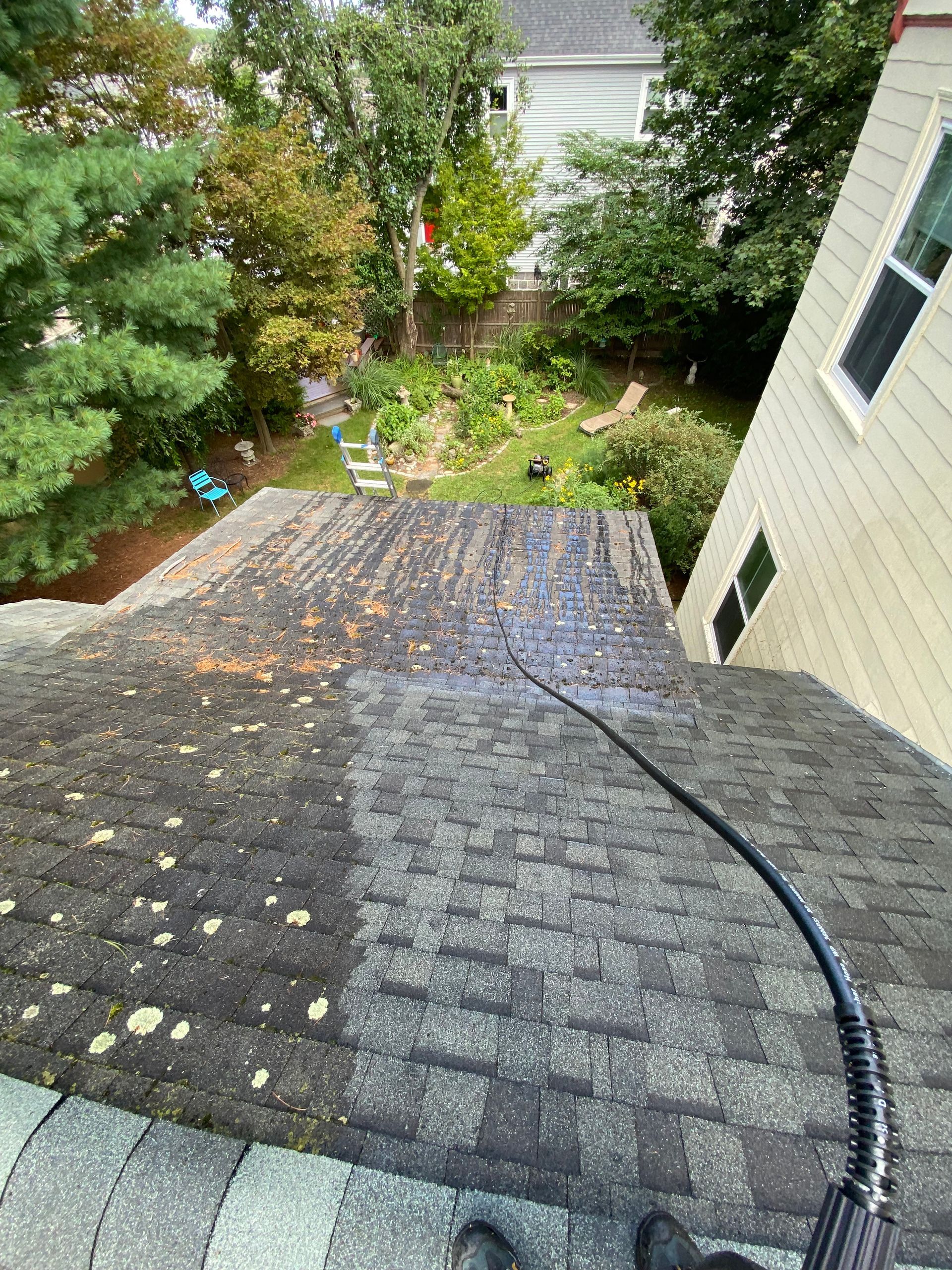 A person is cleaning a roof with a pressure washer.