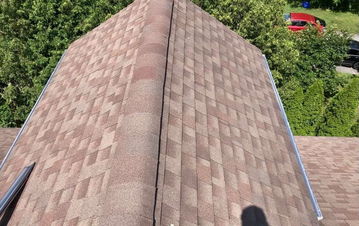 A close up of a roof with a red car parked in the background.
