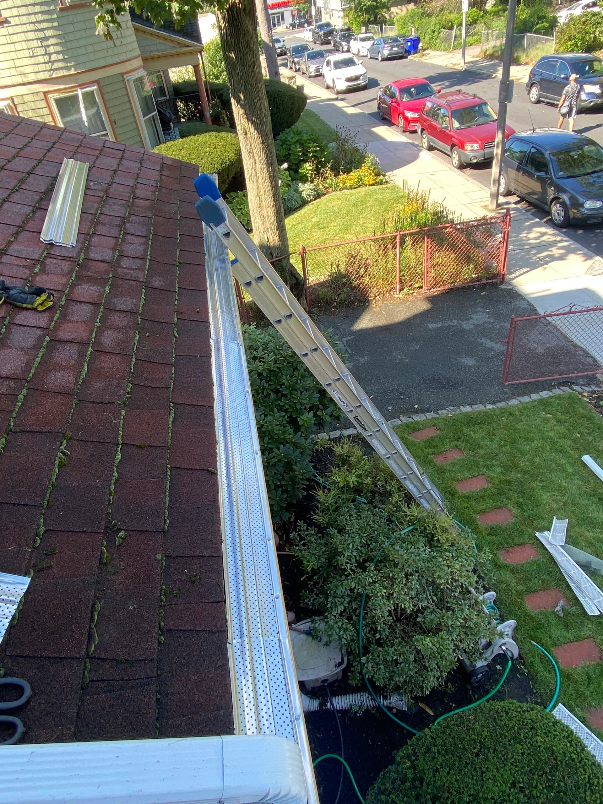 A person is working on a gutter on the roof of a house.