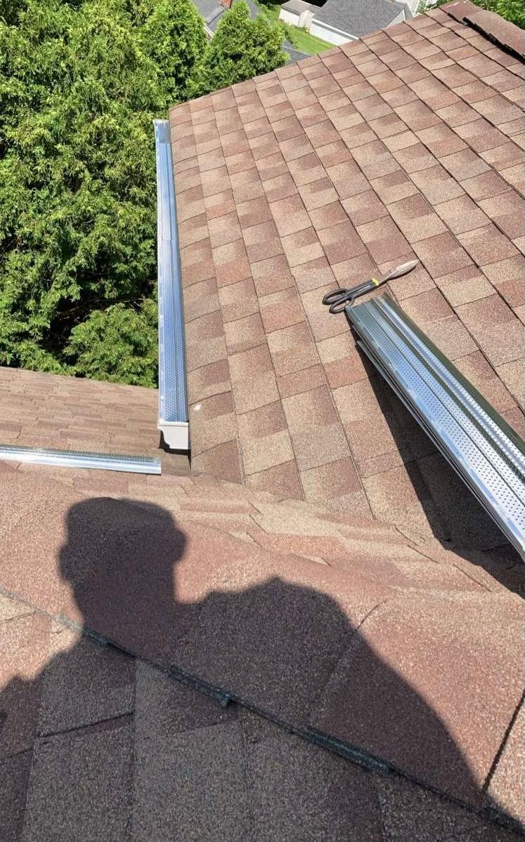A shadow of a person is cast on the roof of a house.