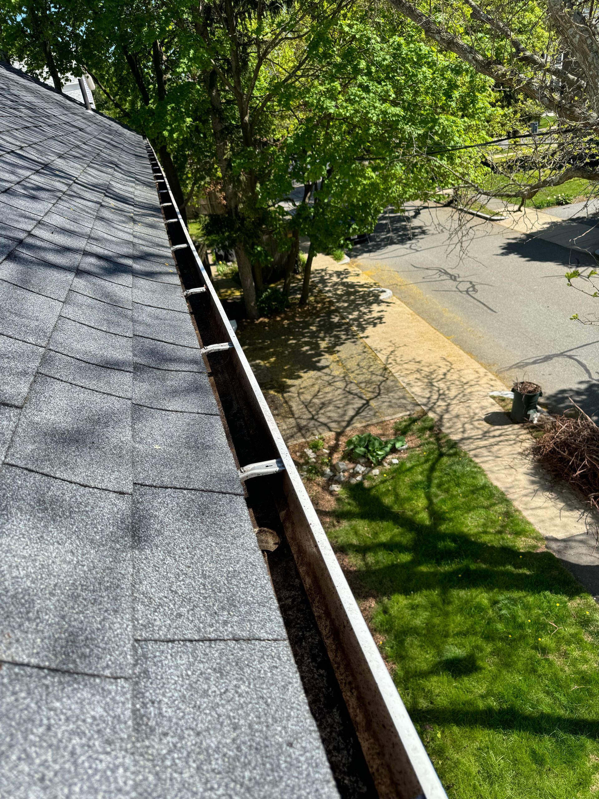 A gutter on the roof of a house with trees in the background.