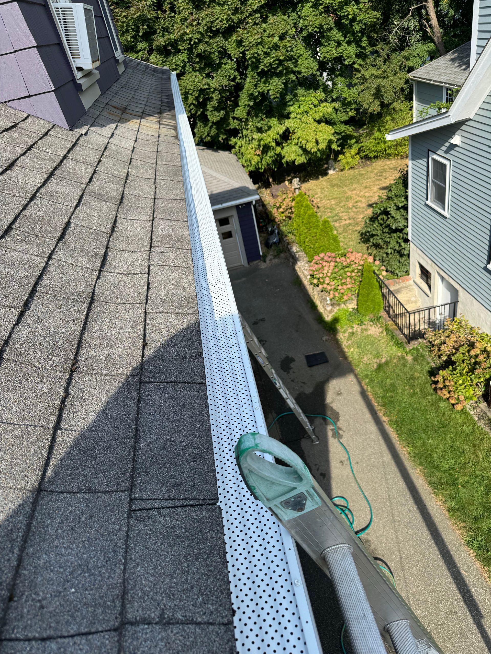A person is cleaning a gutter on the roof of a house.