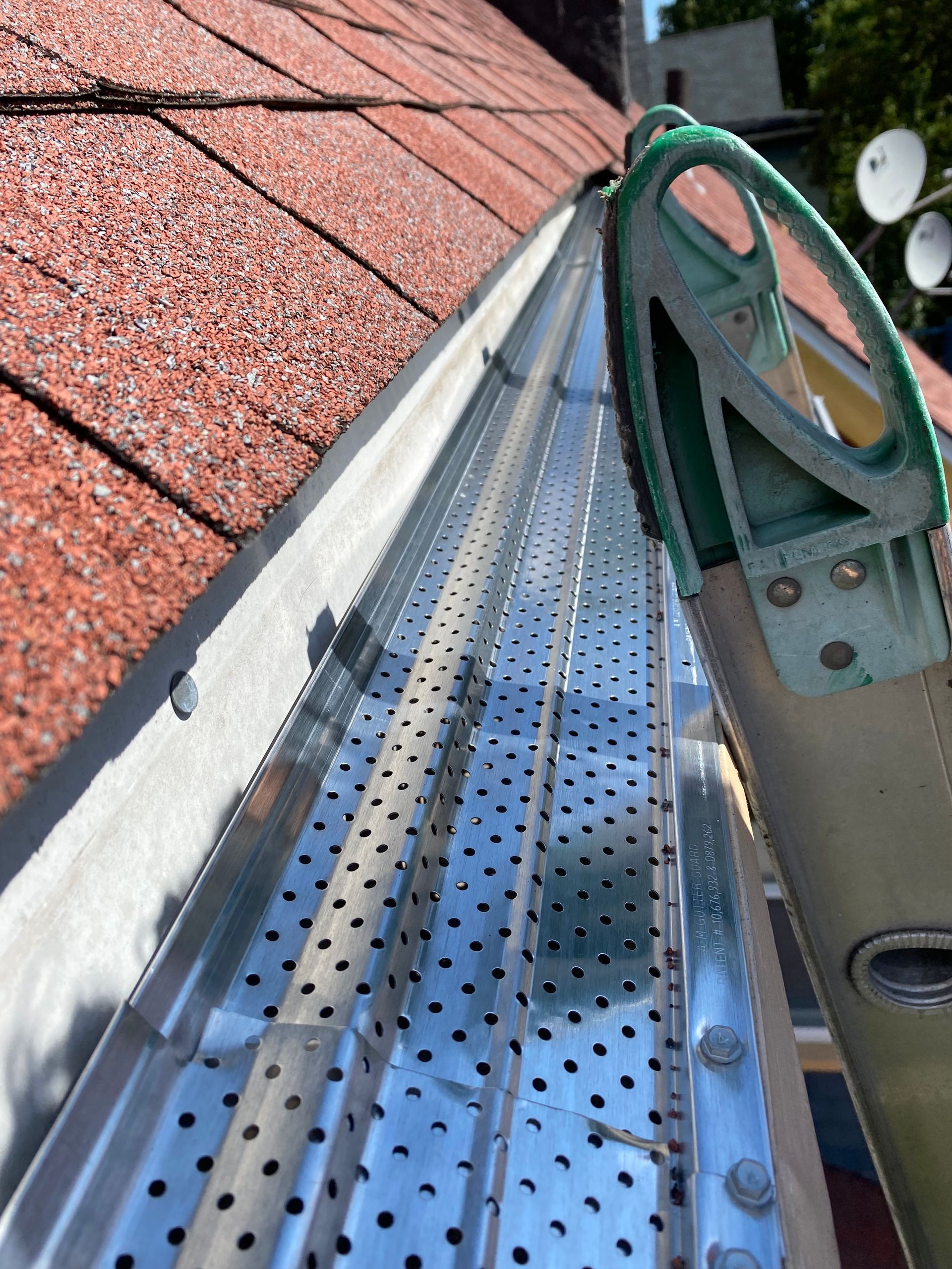 A ladder is sitting on top of a metal gutter on a roof.