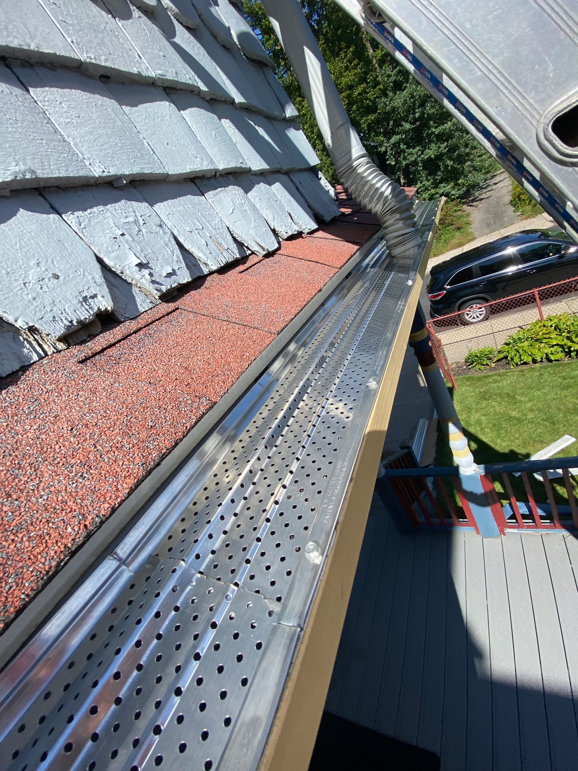 A gutter with holes in it is on the side of a house.
