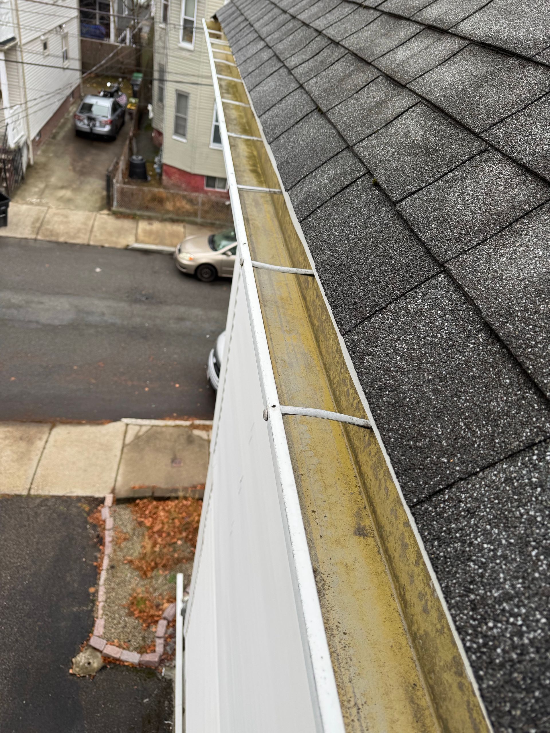 A gutter on the side of a building next to a roof.