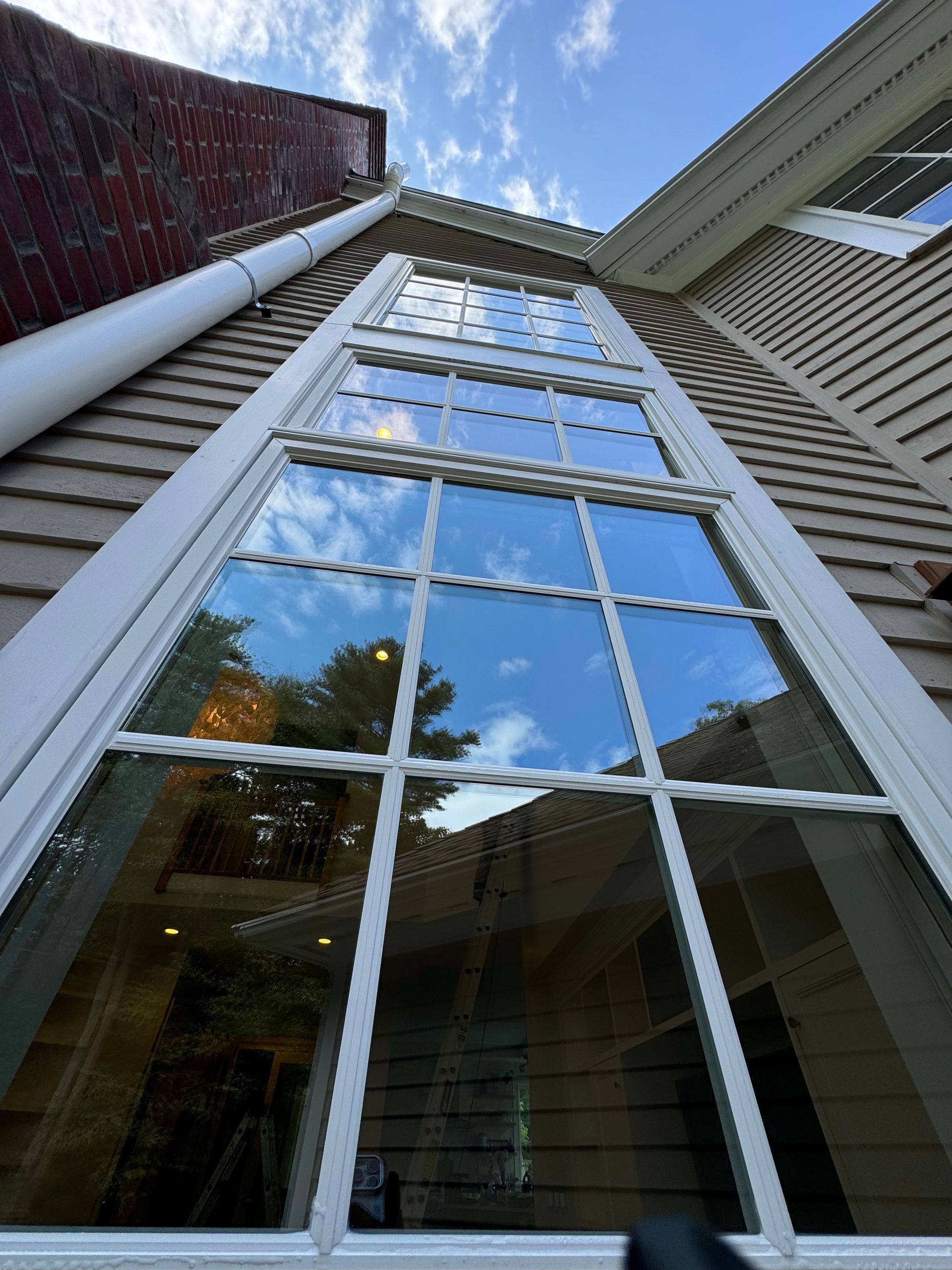 Looking up at a tall window on the side of a house.