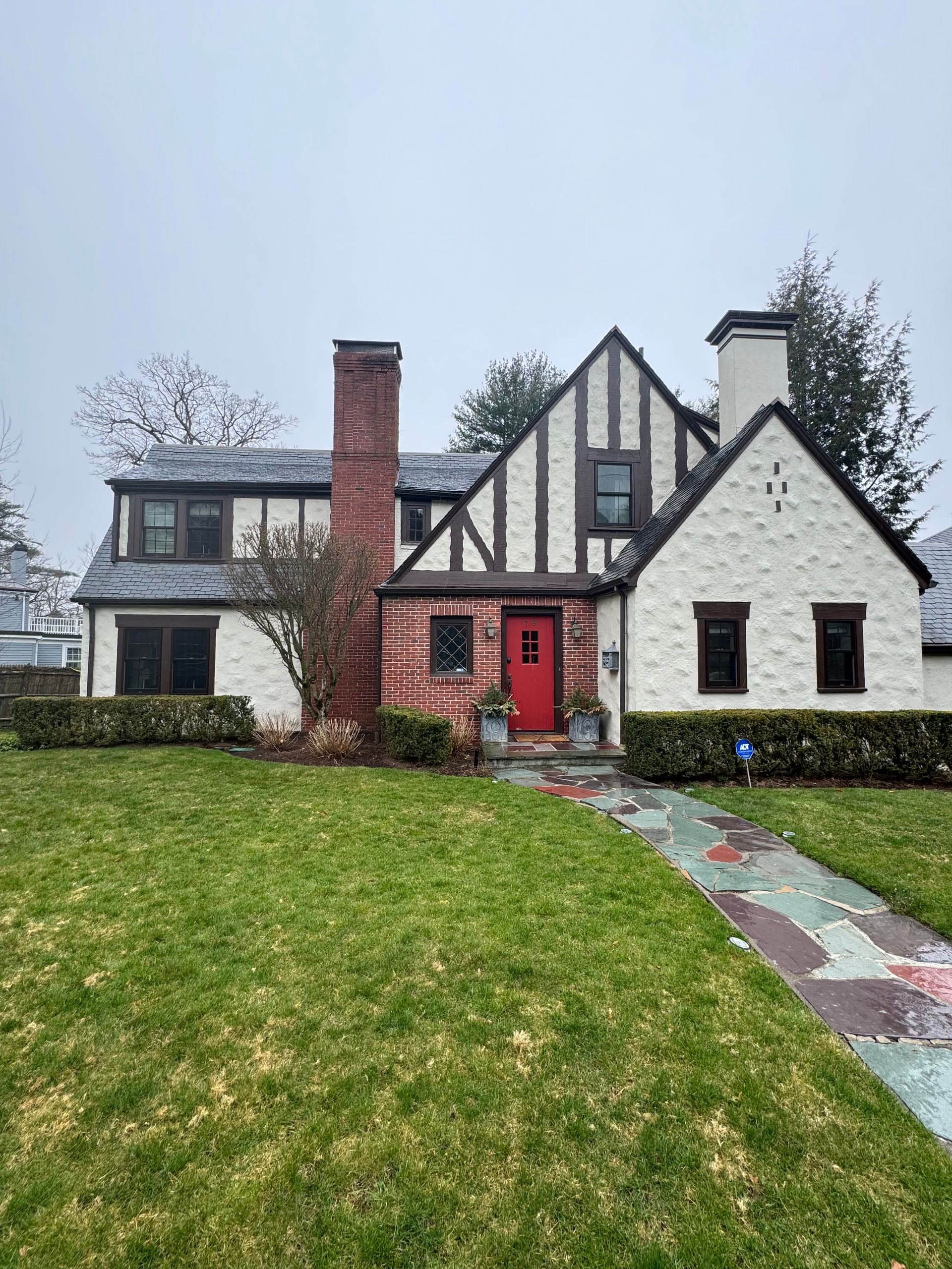 A white and black house with a red door and chimney.