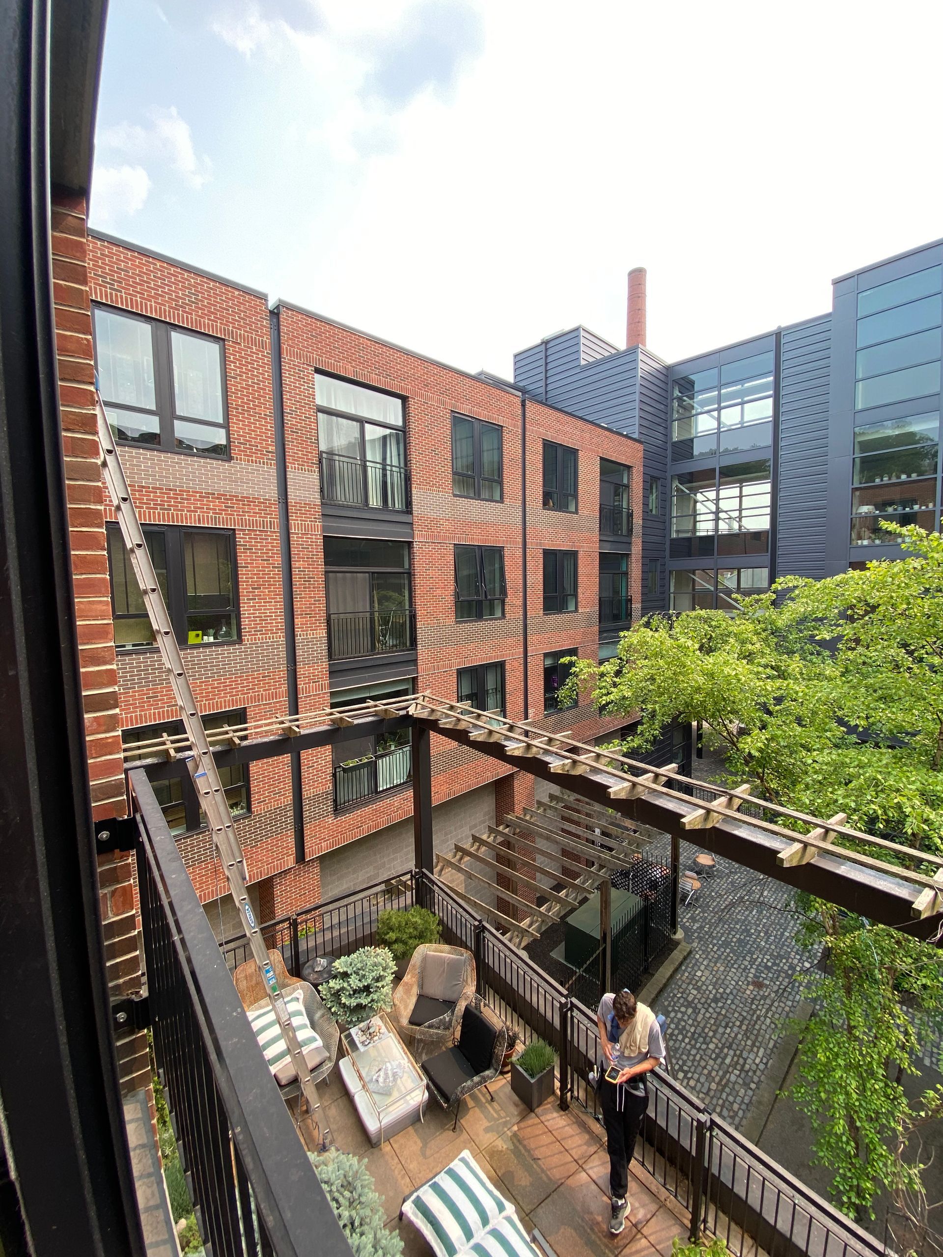 A woman is standing on a balcony overlooking a brick building.