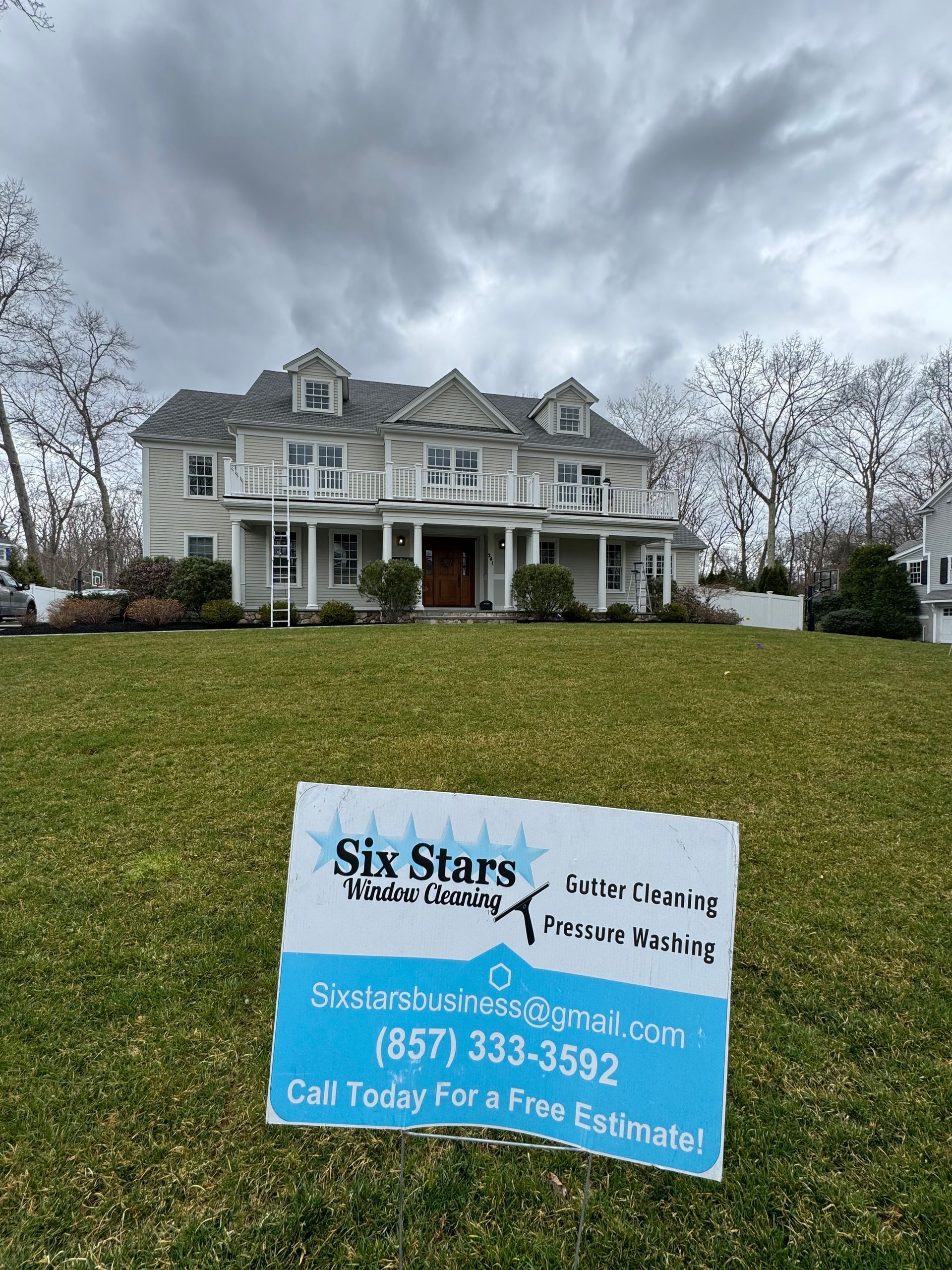 A six stars roofing sign is in front of a large house.