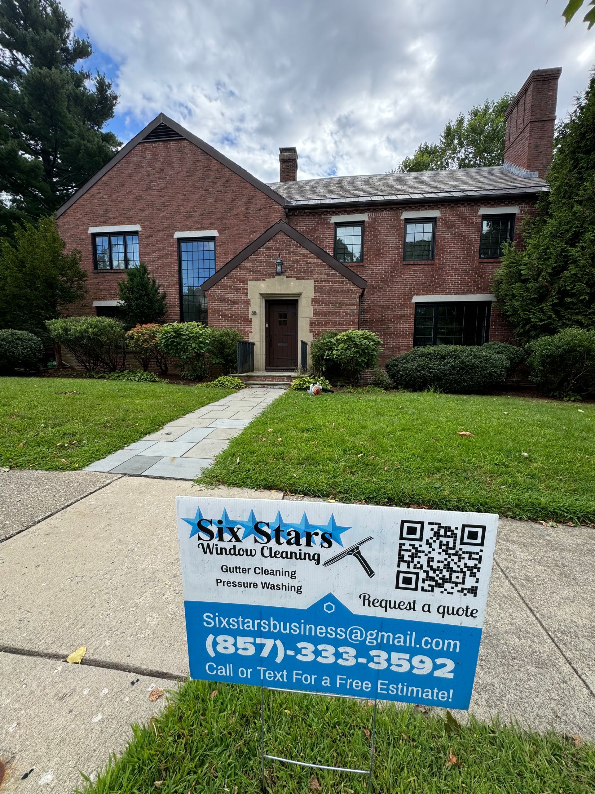 A brick house with a sign in front of it.