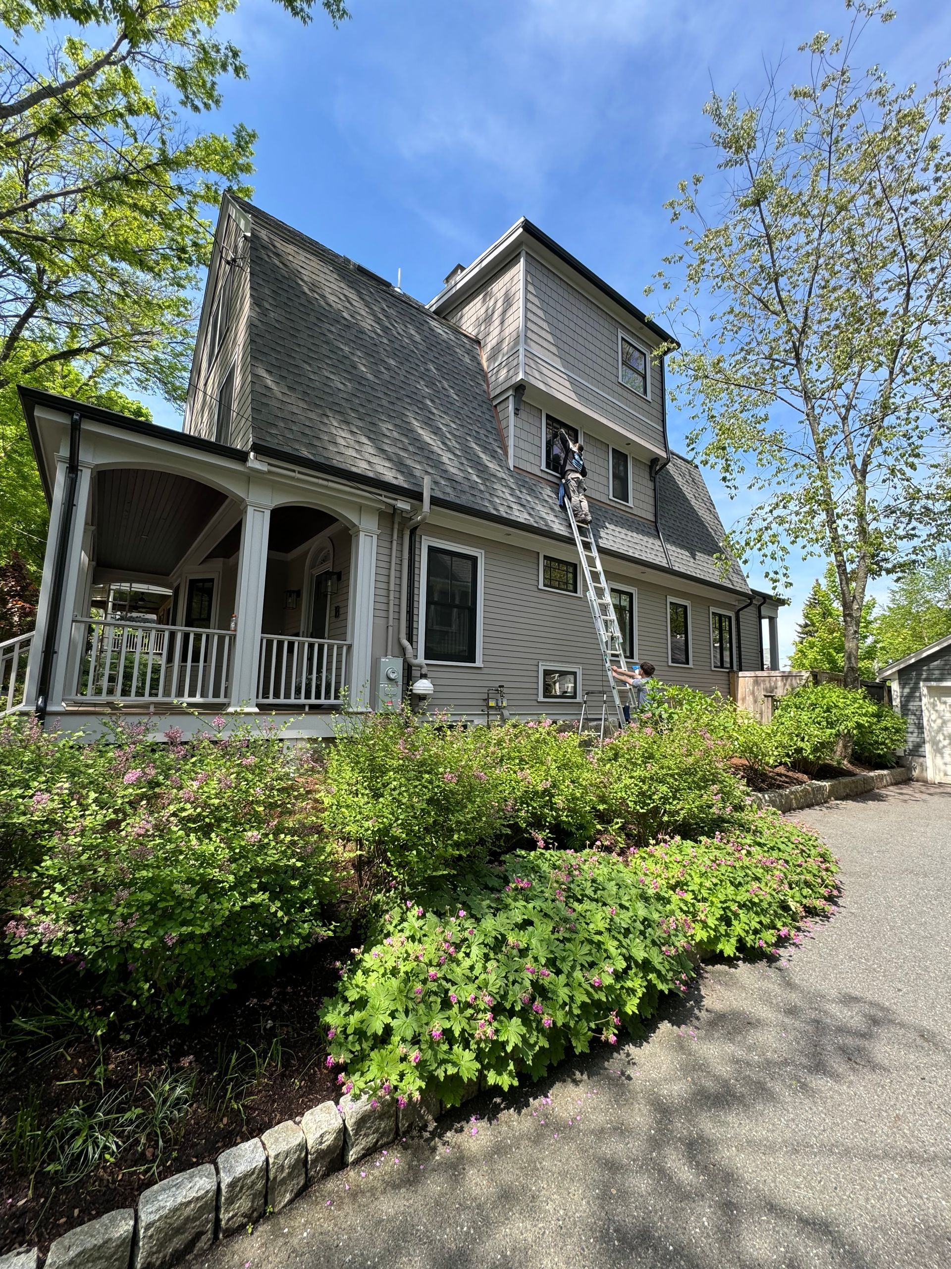 A large house with a ladder on the side of it is being painted.