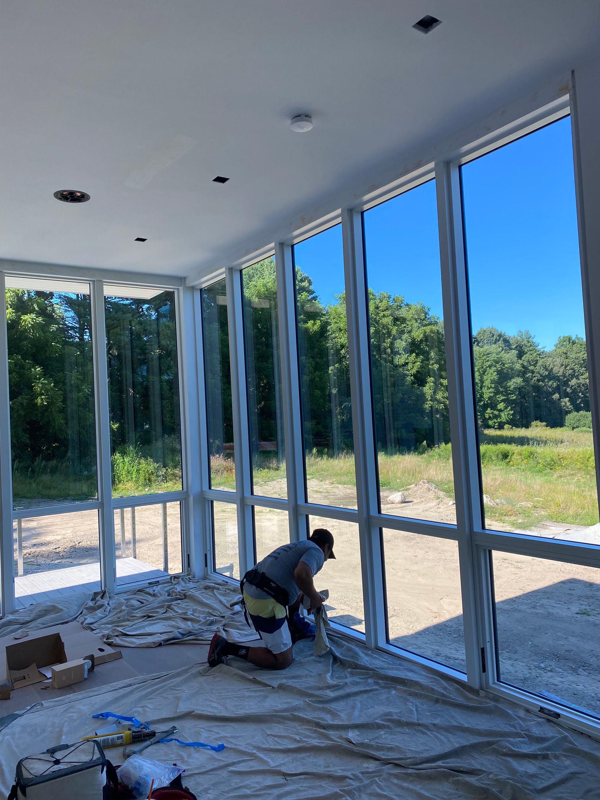 A man is kneeling in a room with a lot of windows.