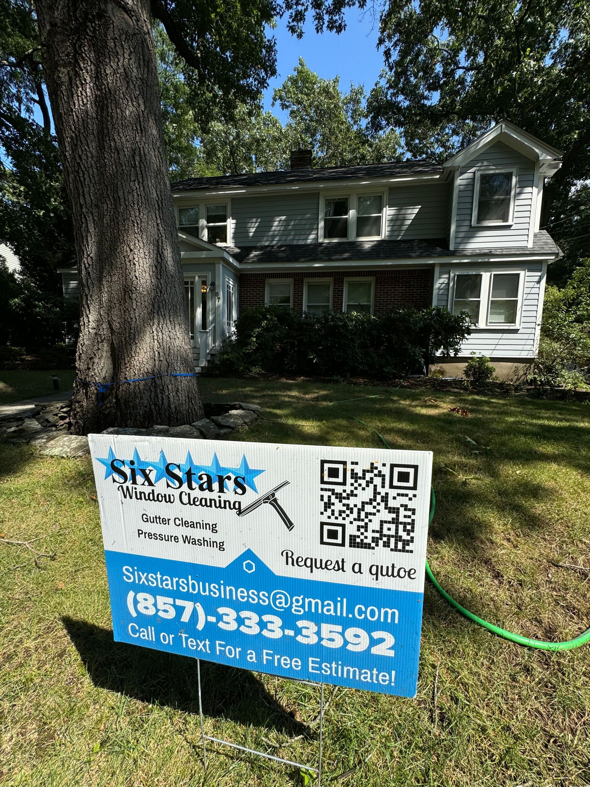 A sign is sitting in front of a house with a qr code on it.