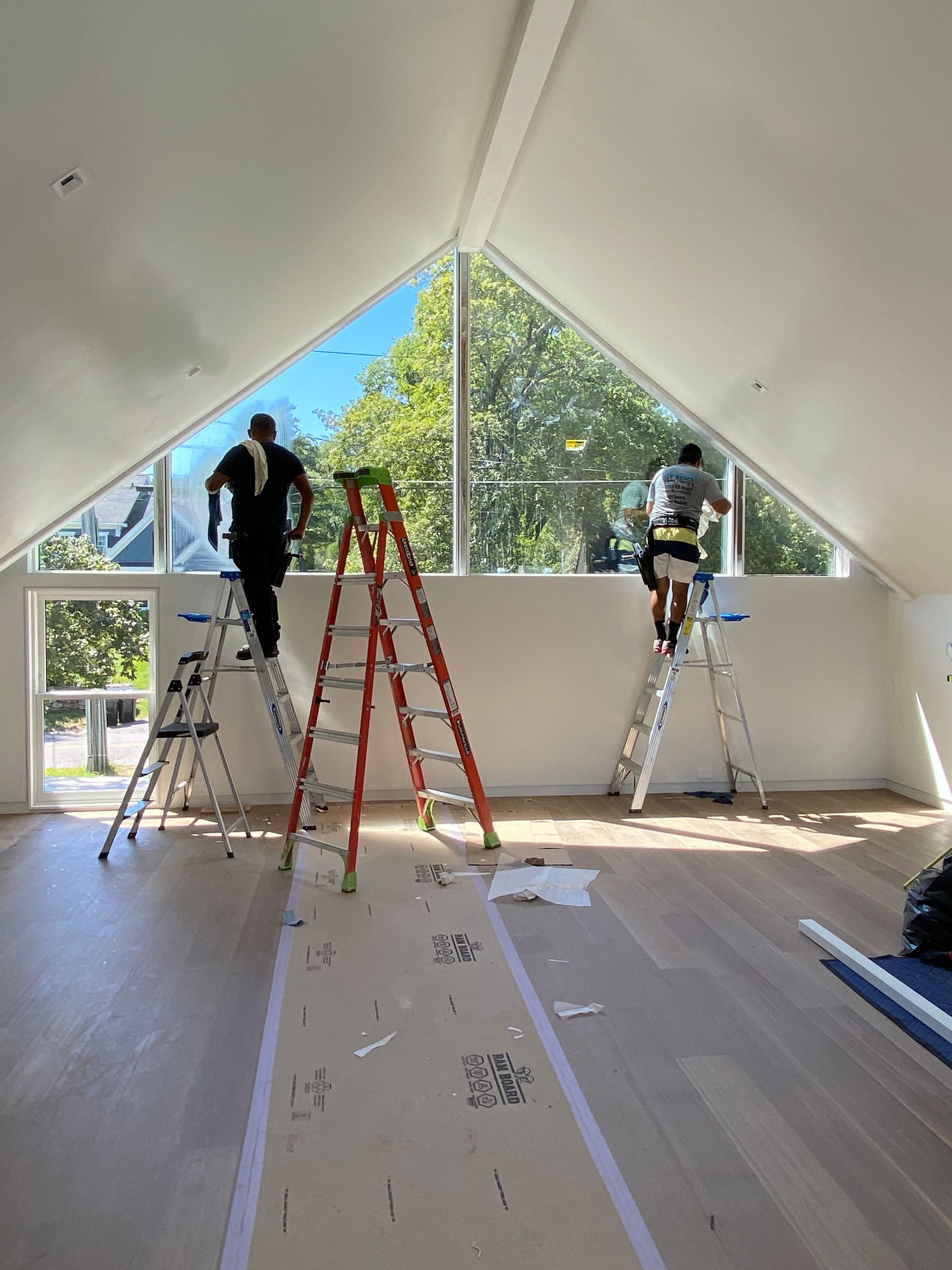 Two men are standing on ladders in a room.