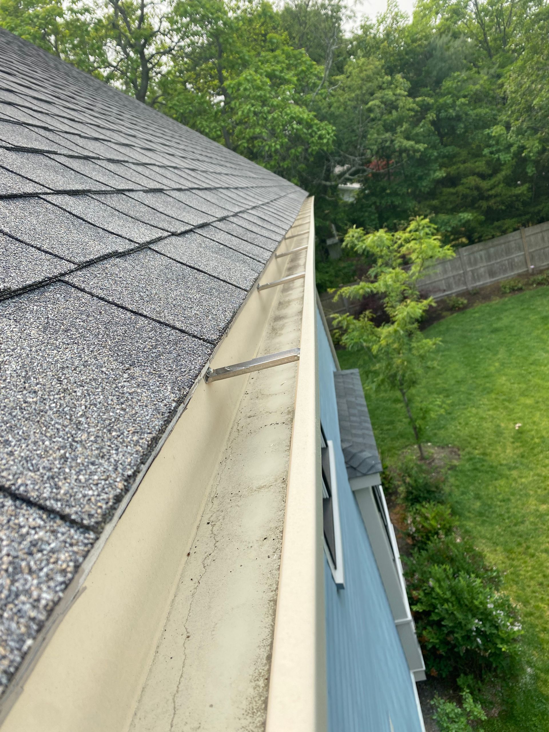 A gutter on the side of a house next to a roof.