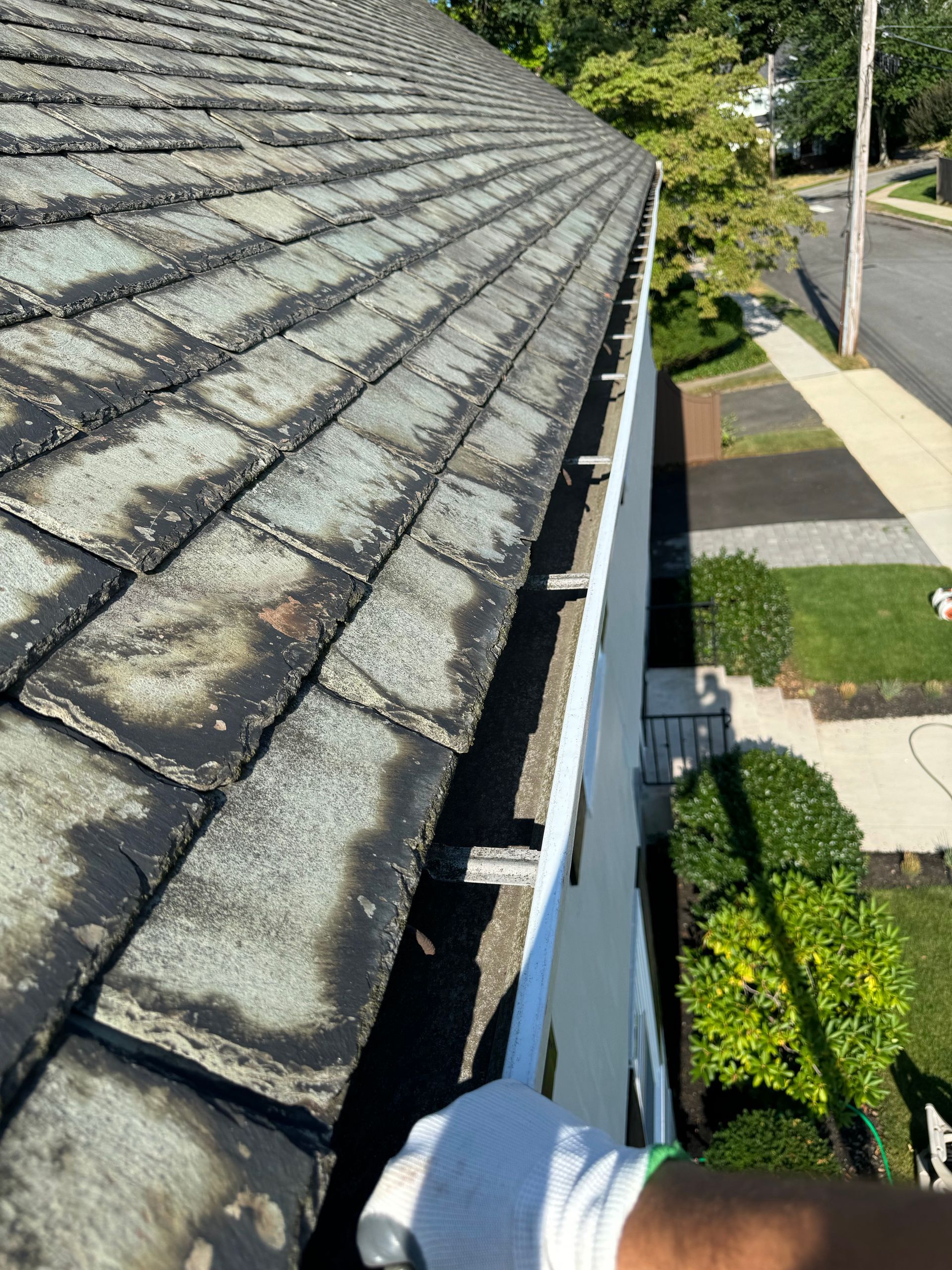 A person is cleaning a gutter on the roof of a house.