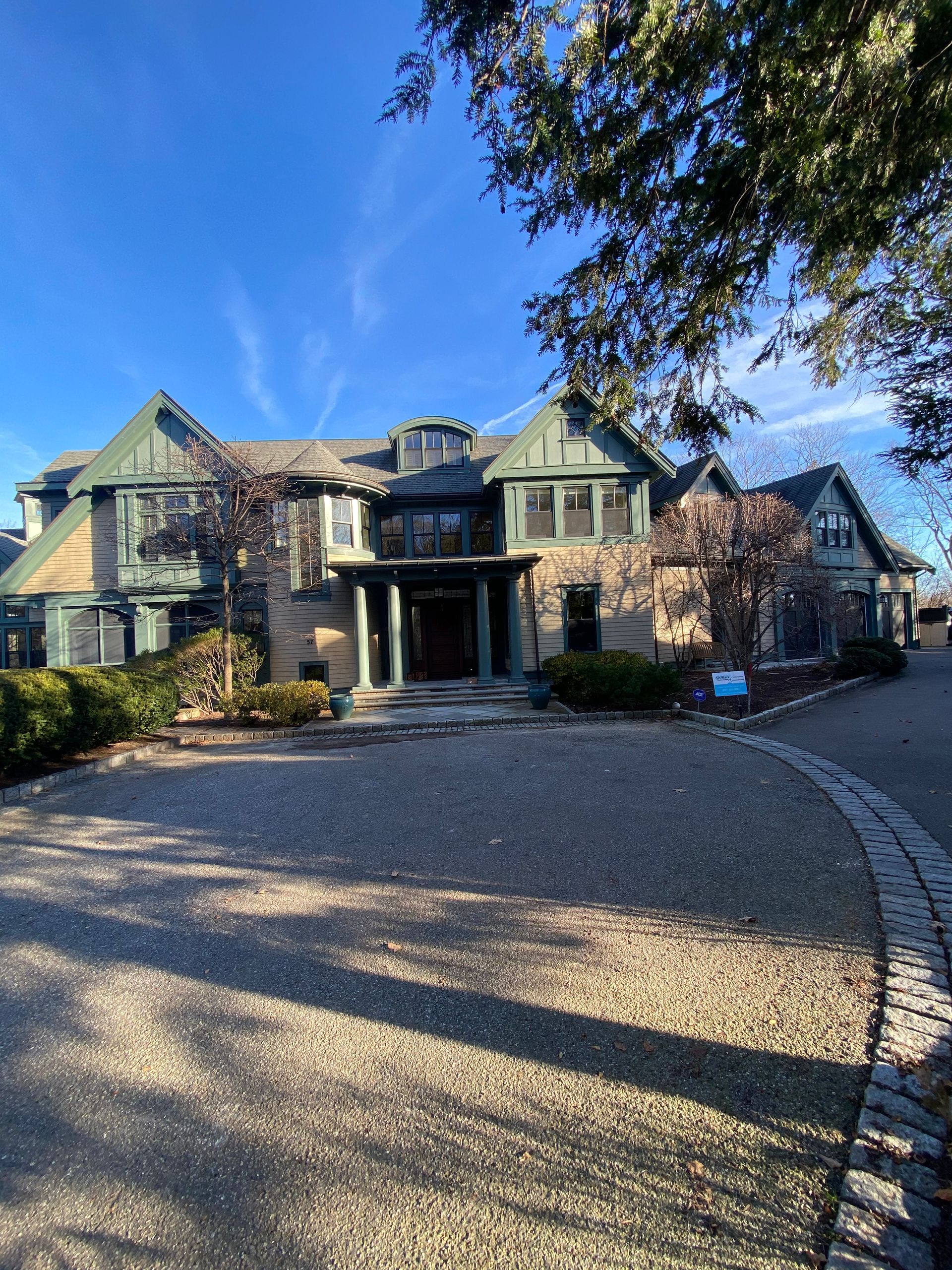A large house with a gravel driveway in front of it.