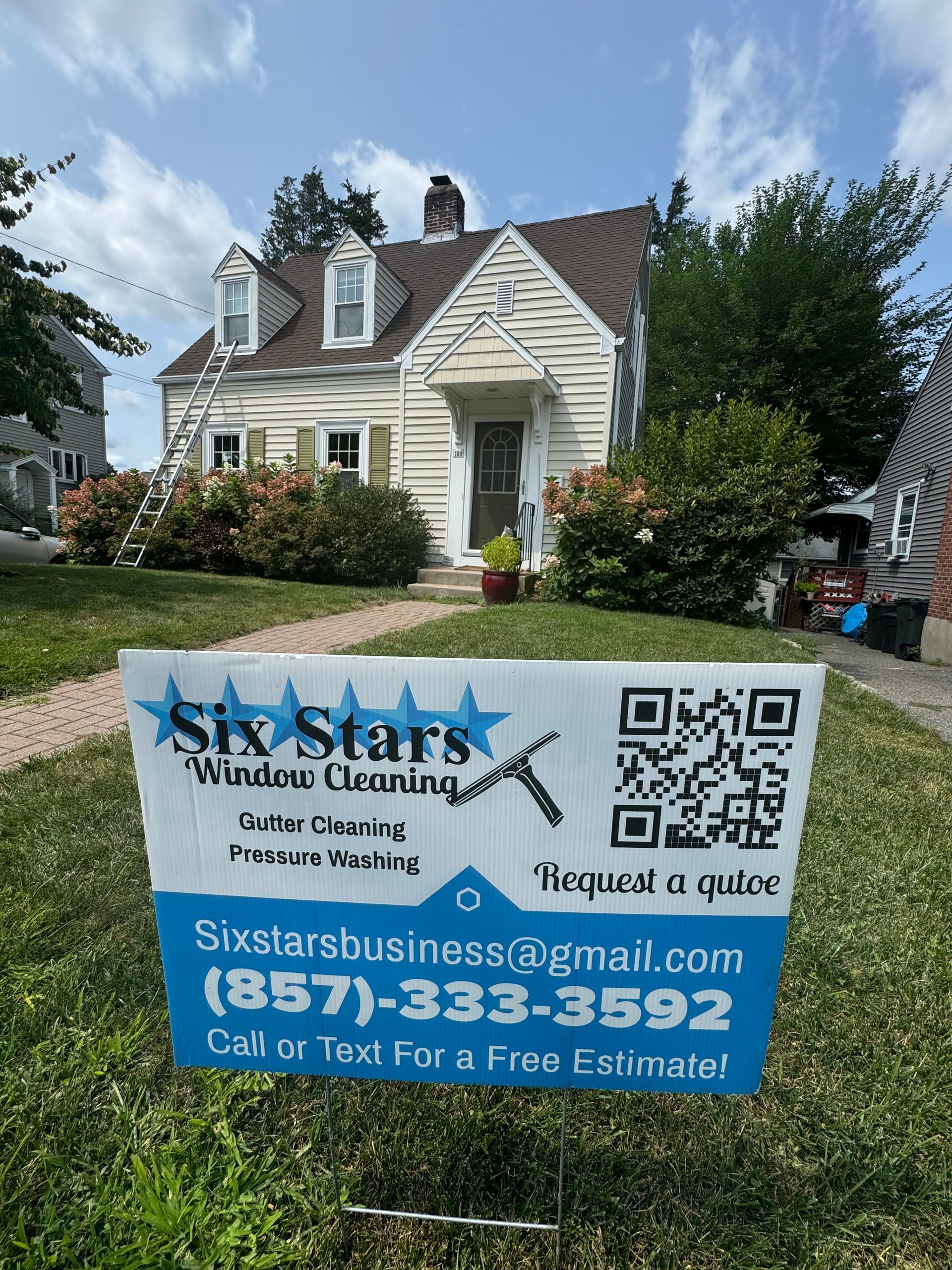 A sign for six stars window cleaning is in front of a house.