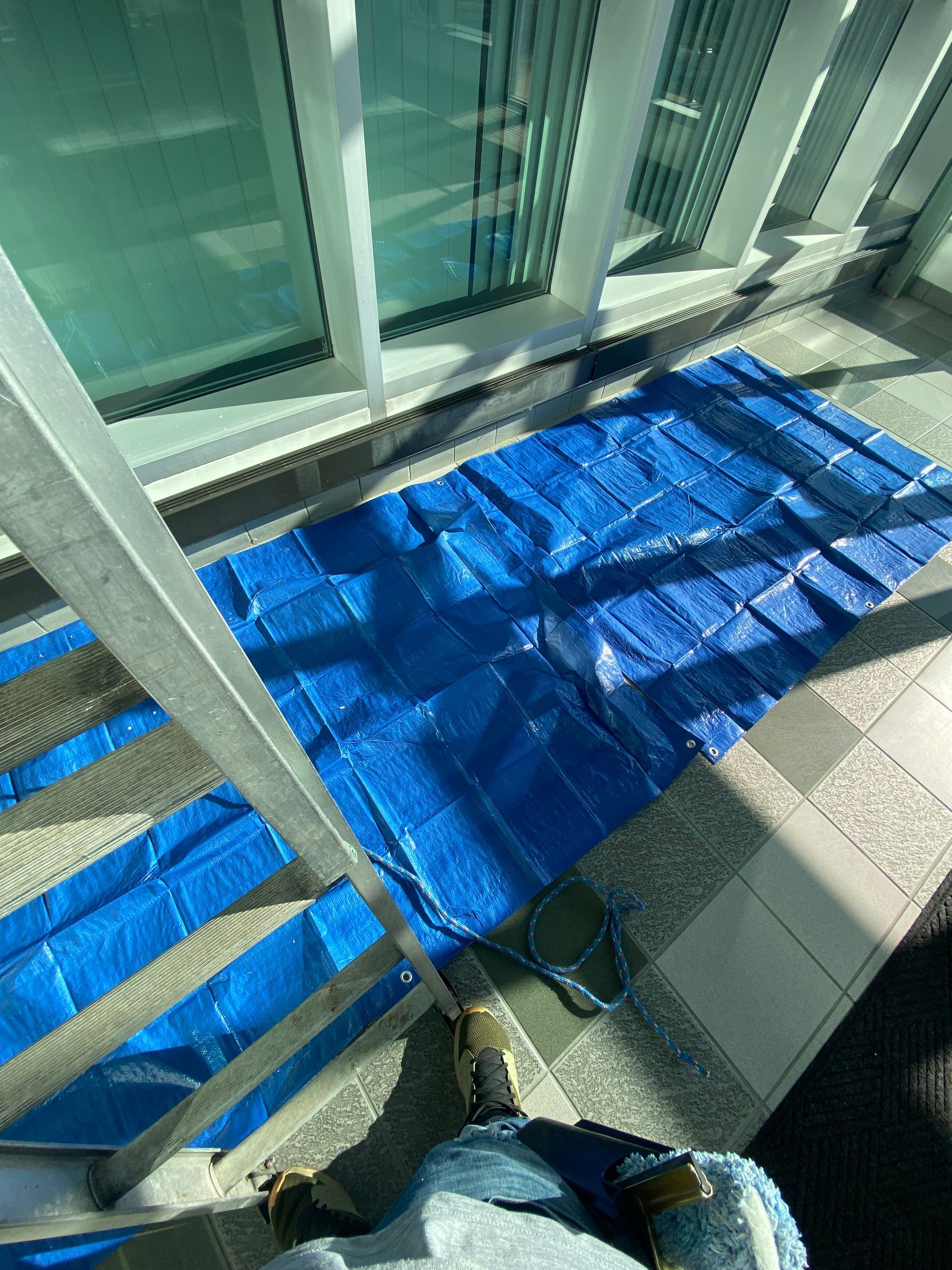 A person is standing on a staircase next to a blue tarp.