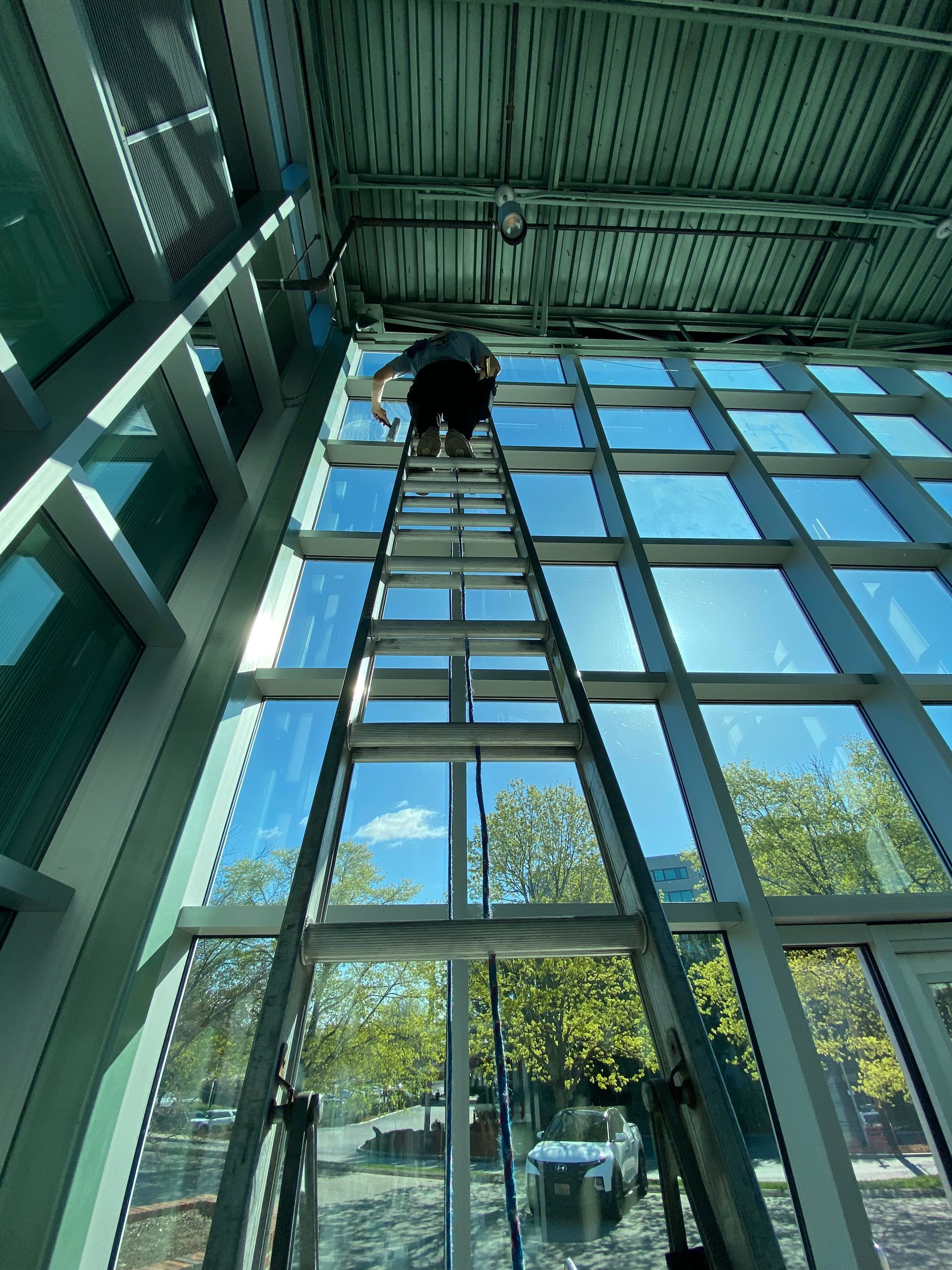 A man is standing on a ladder cleaning the windows of a building.
