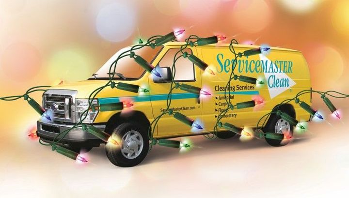 A yellow Servicemaster van is decorated with Christmas lights