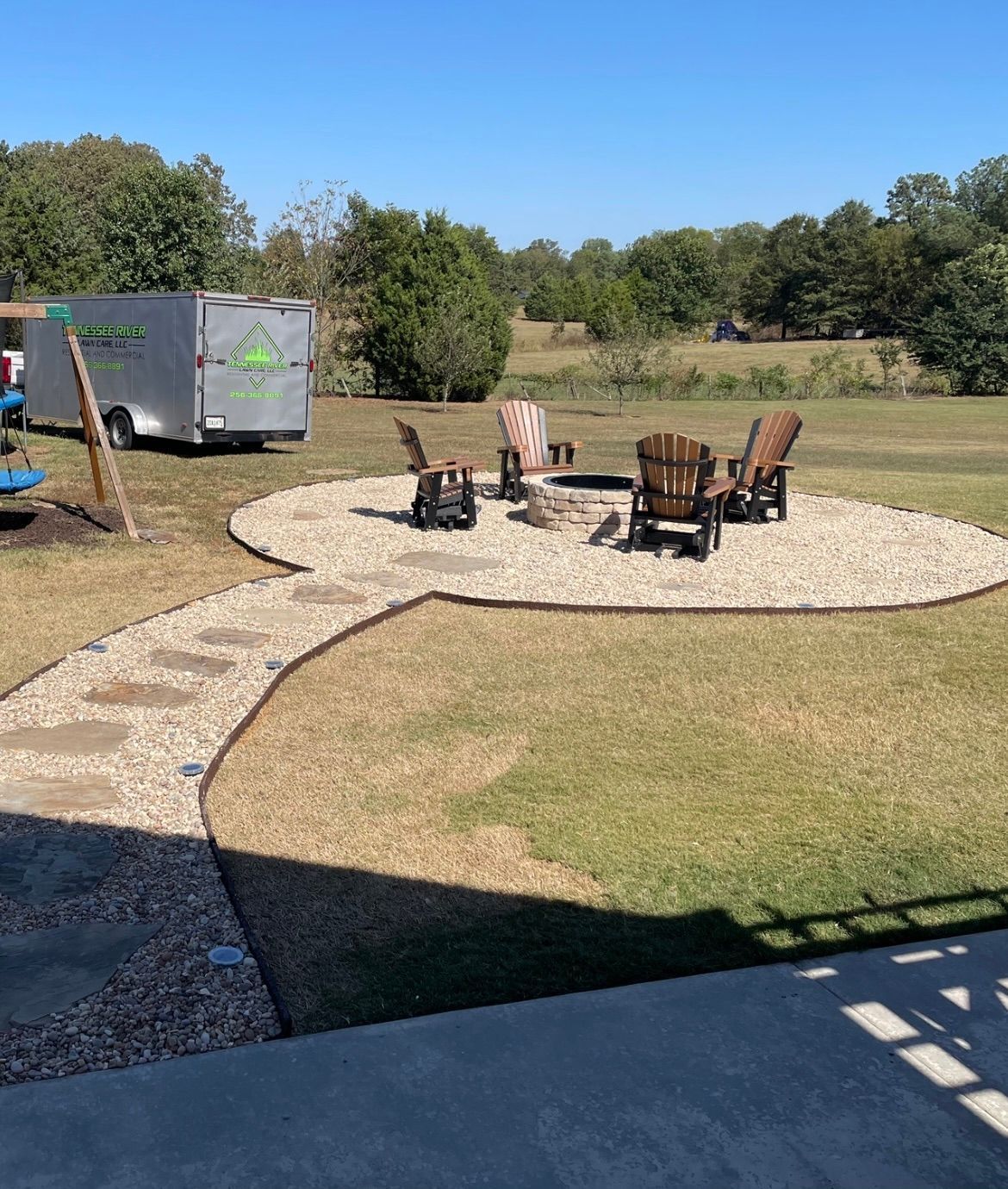 A fire pit in the middle of the yard with chairs around it 