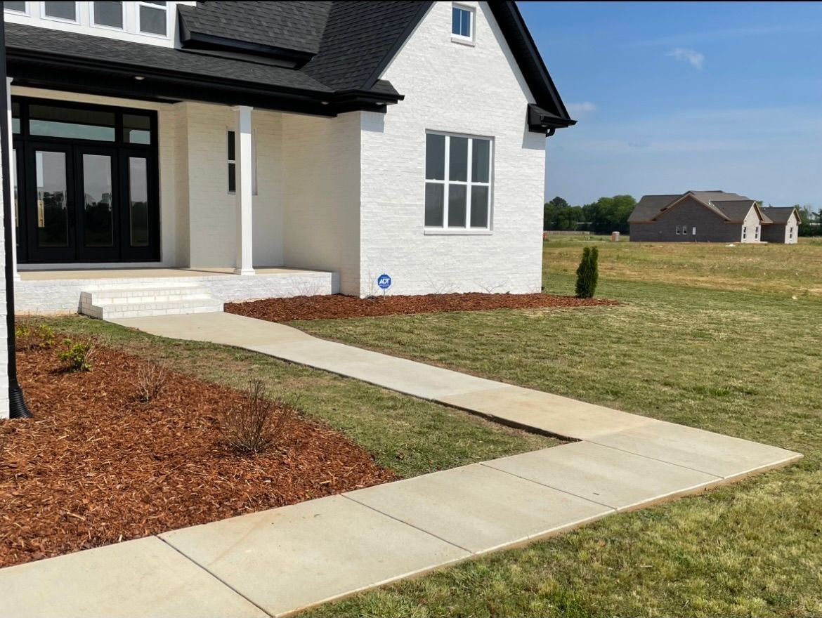 a white house with a black roof and a walkway leading to it