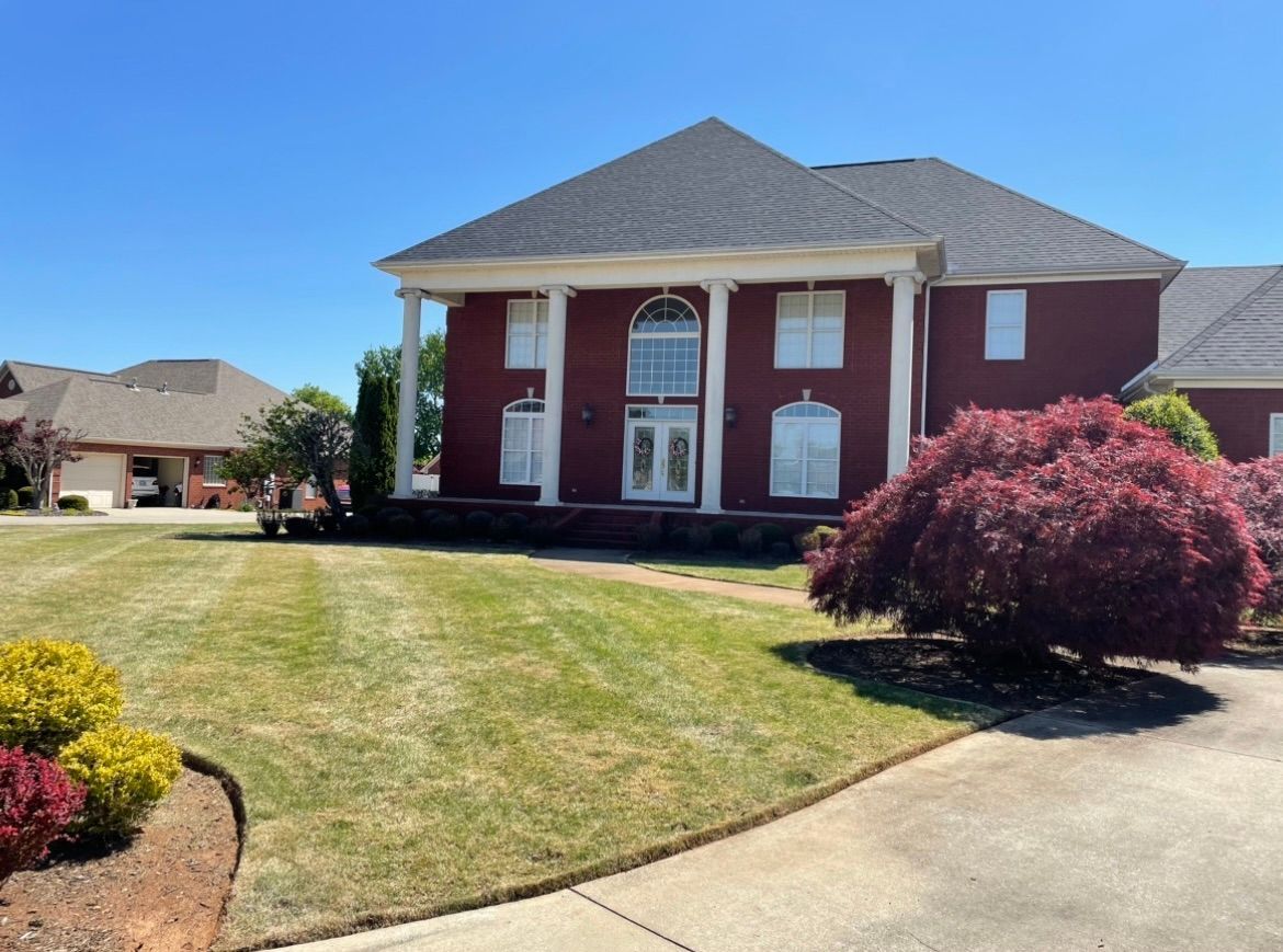 A large red house with a lush green lawn in front of it