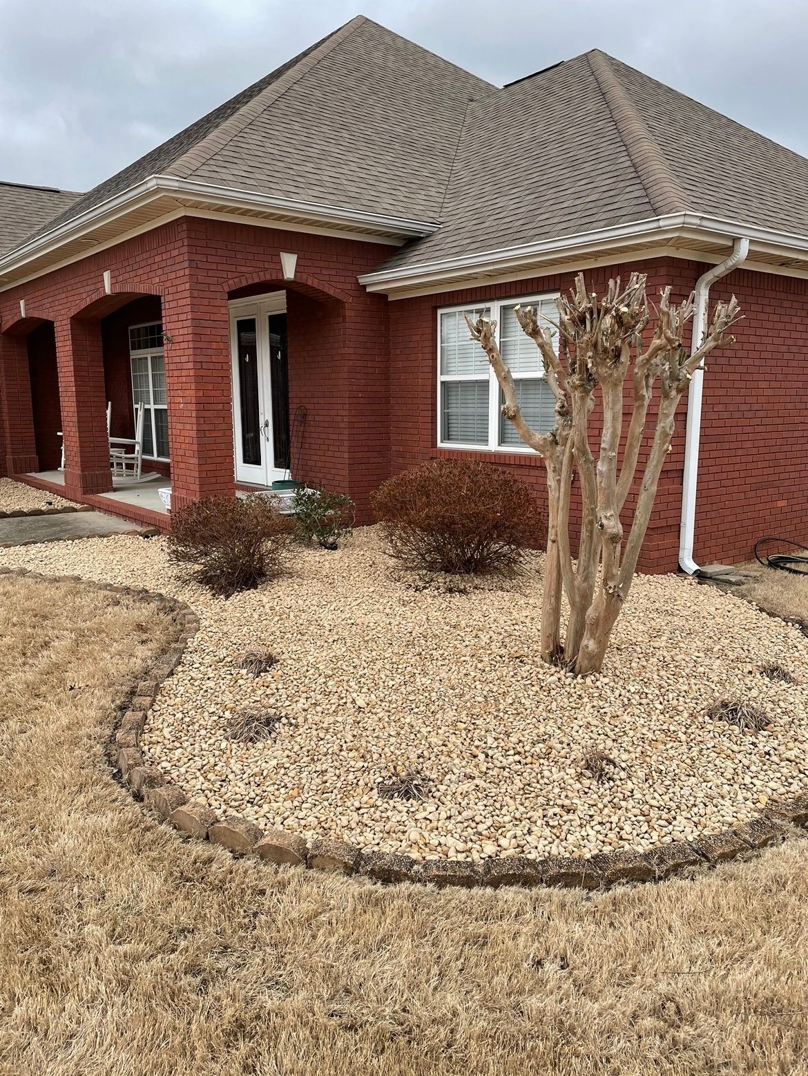 A red brick house with a gravel yard in front of it