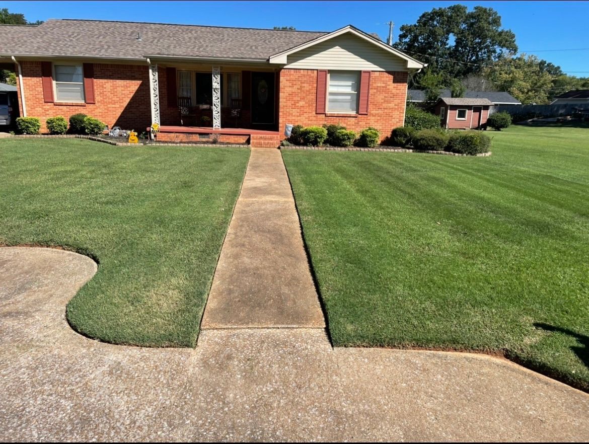 Brick house with a lush green lawn and a walkway leading to it