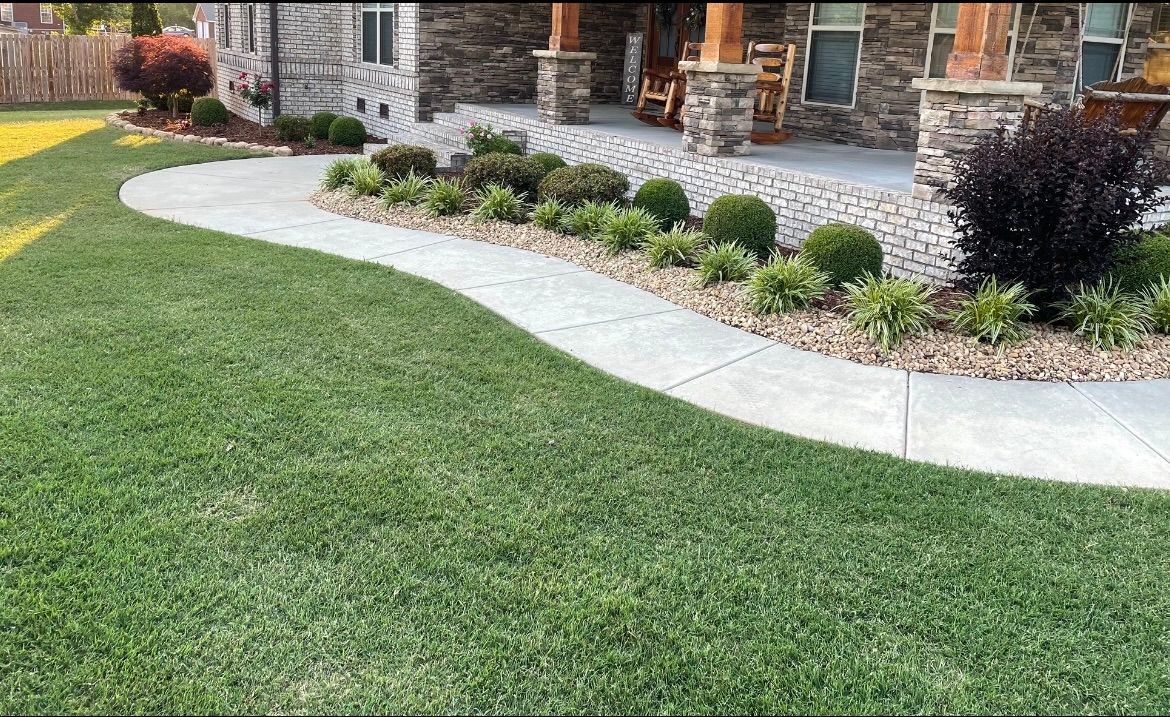 A walkway leading to a house with a lush green lawn