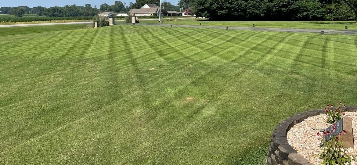 A lush green lawn is being mowed by a lawn mower