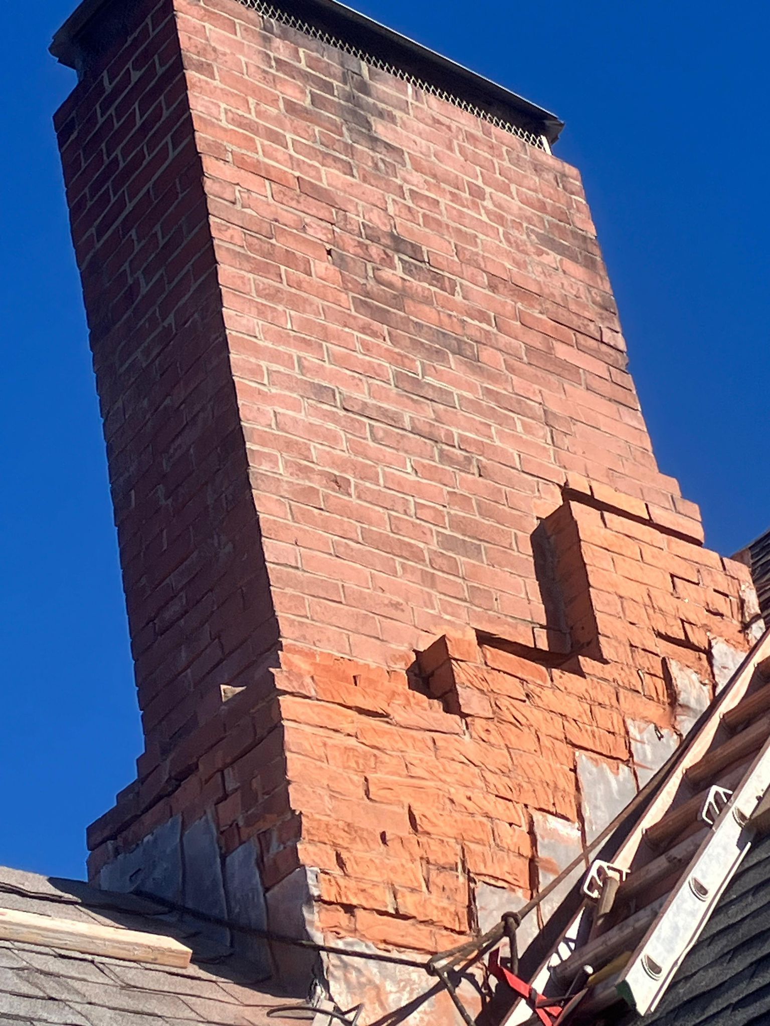 A large brick chimney is sitting on top of a roof.