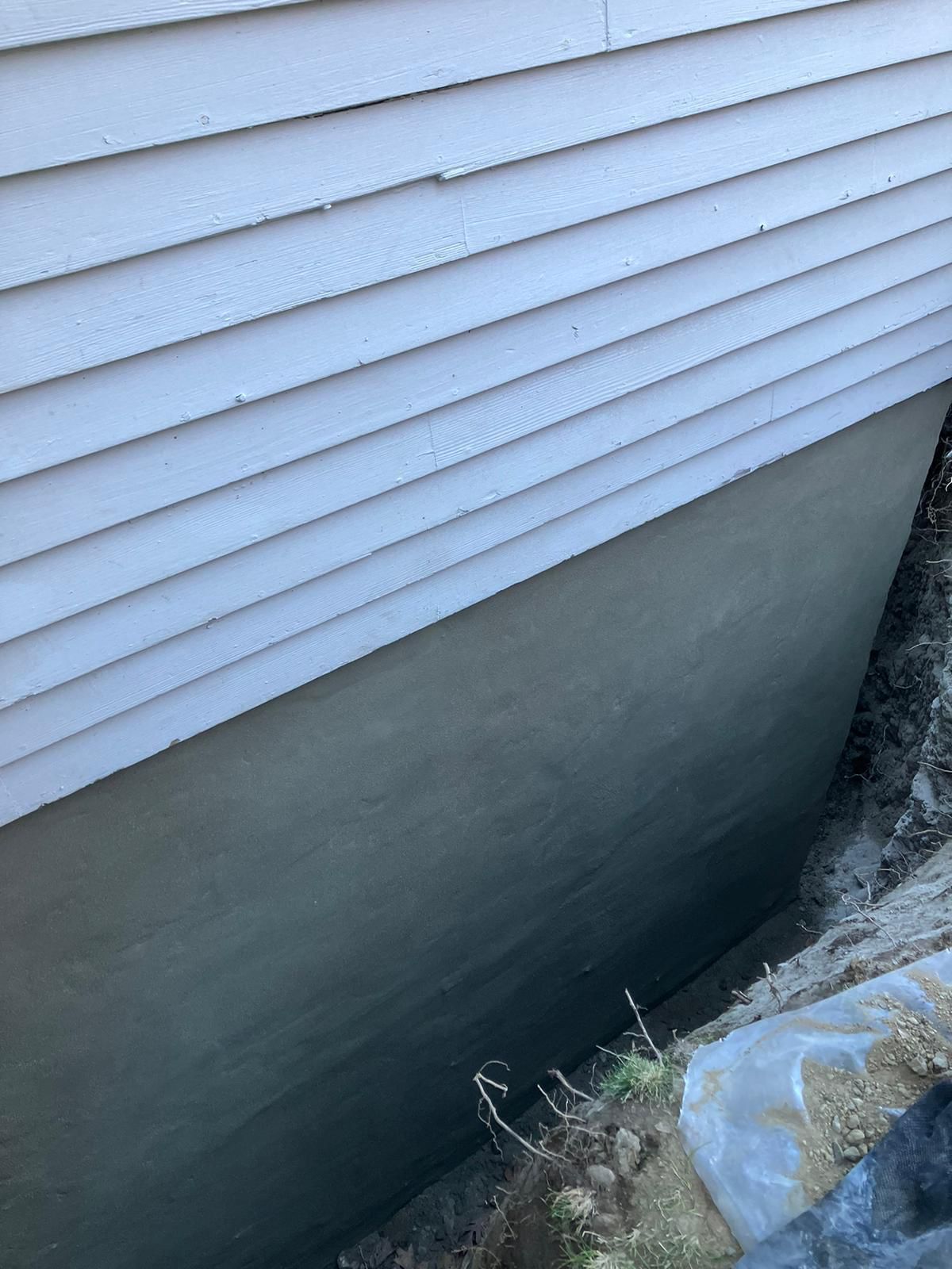 A white house with a concrete foundation underneath it.