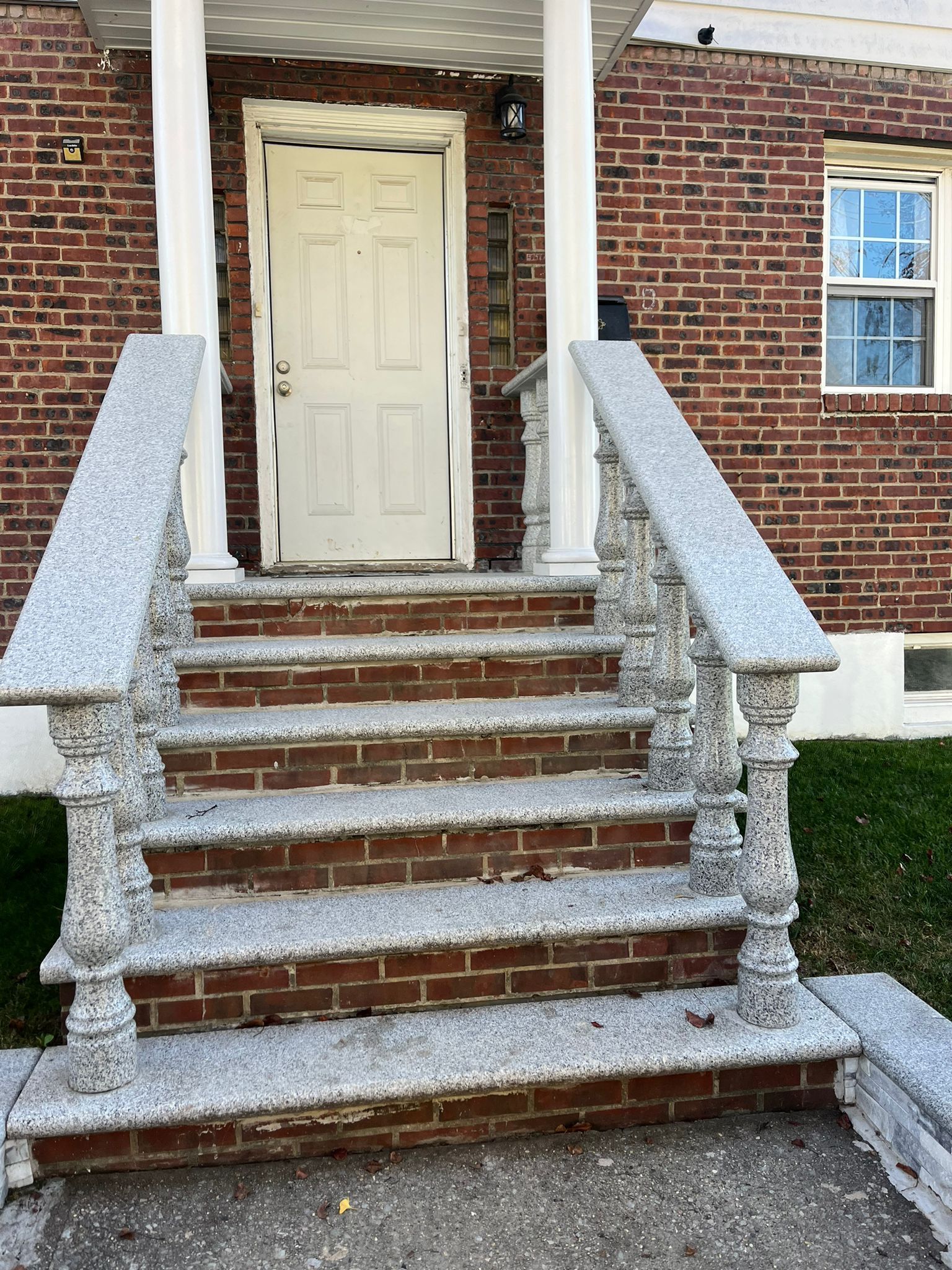 There are stairs leading up to the front door of a brick house.