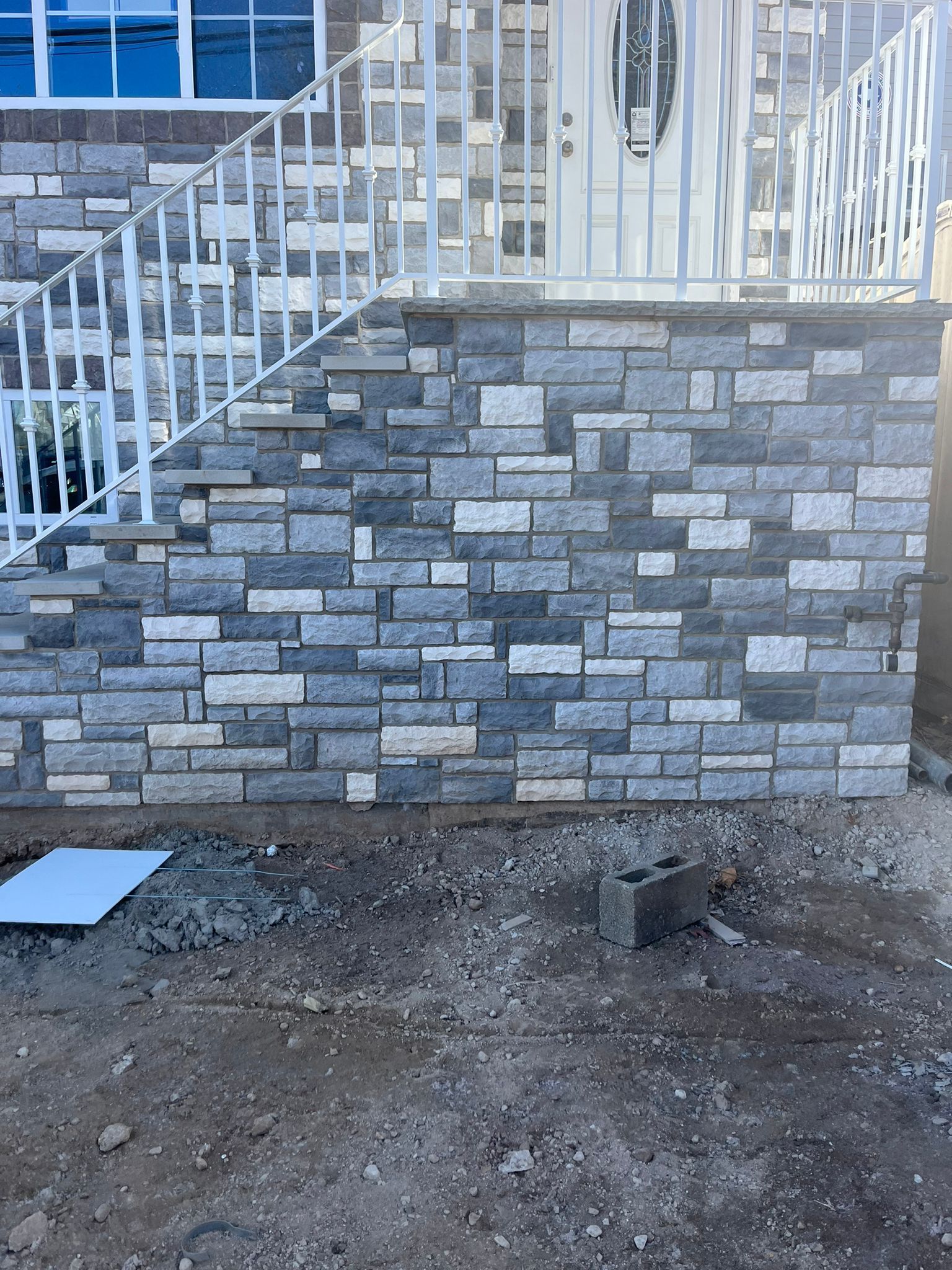 A brick wall with stairs leading up to it in front of a house.