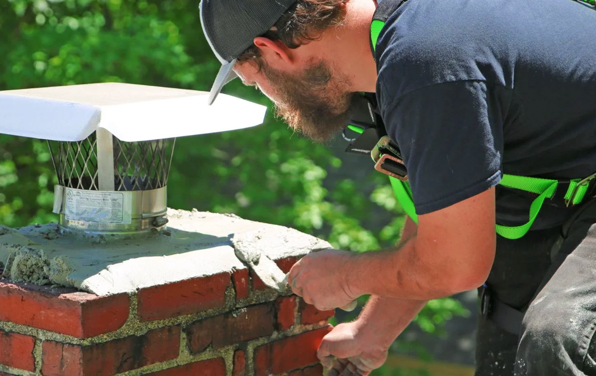 A man is working on a brick chimney with a trowel.