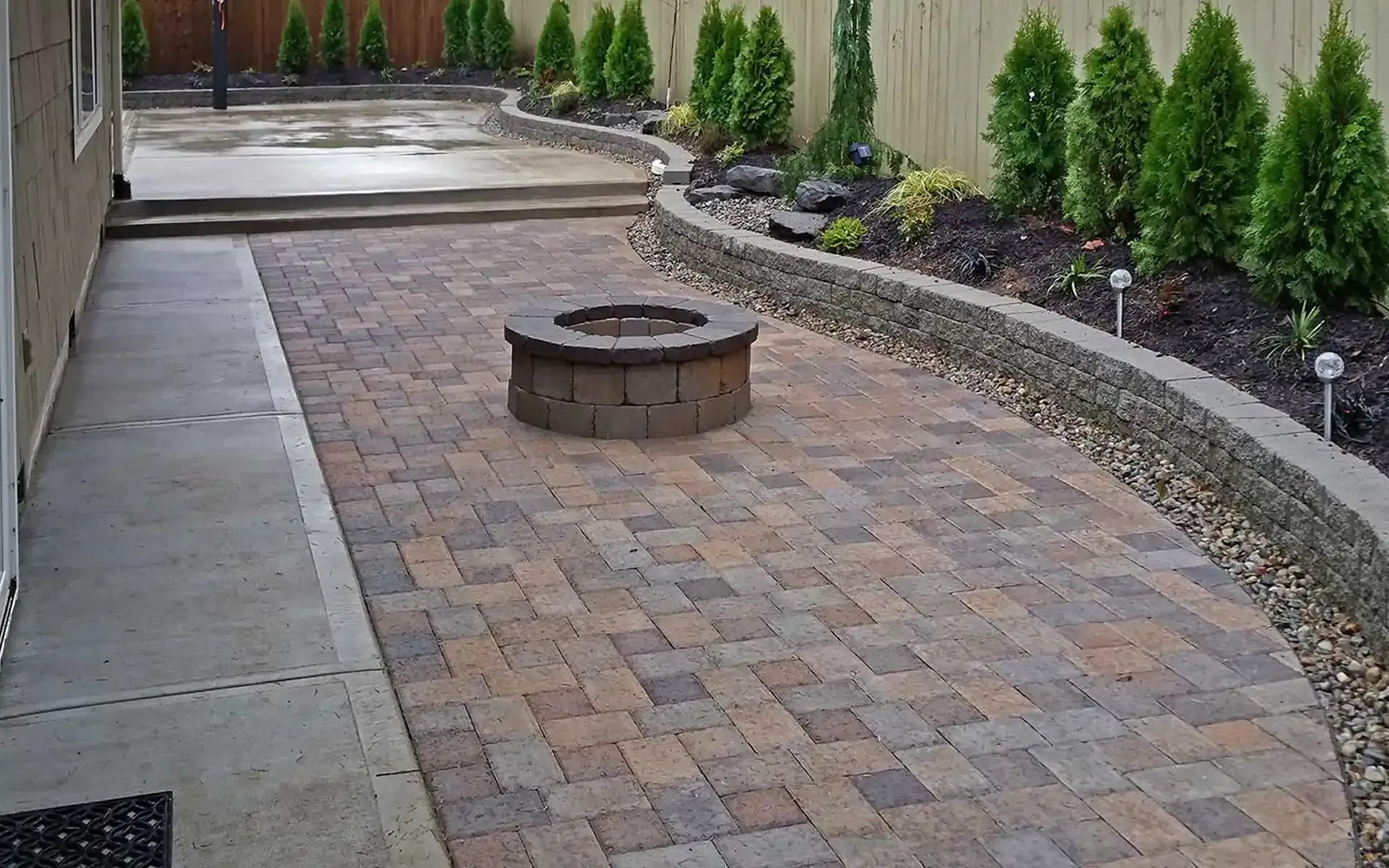 A brick patio with a fire pit in the middle