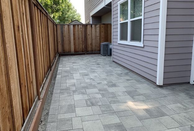 A house with a wooden fence and a patio in front of it.