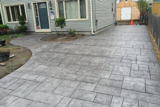 A concrete driveway leading to a house with a blue door.
